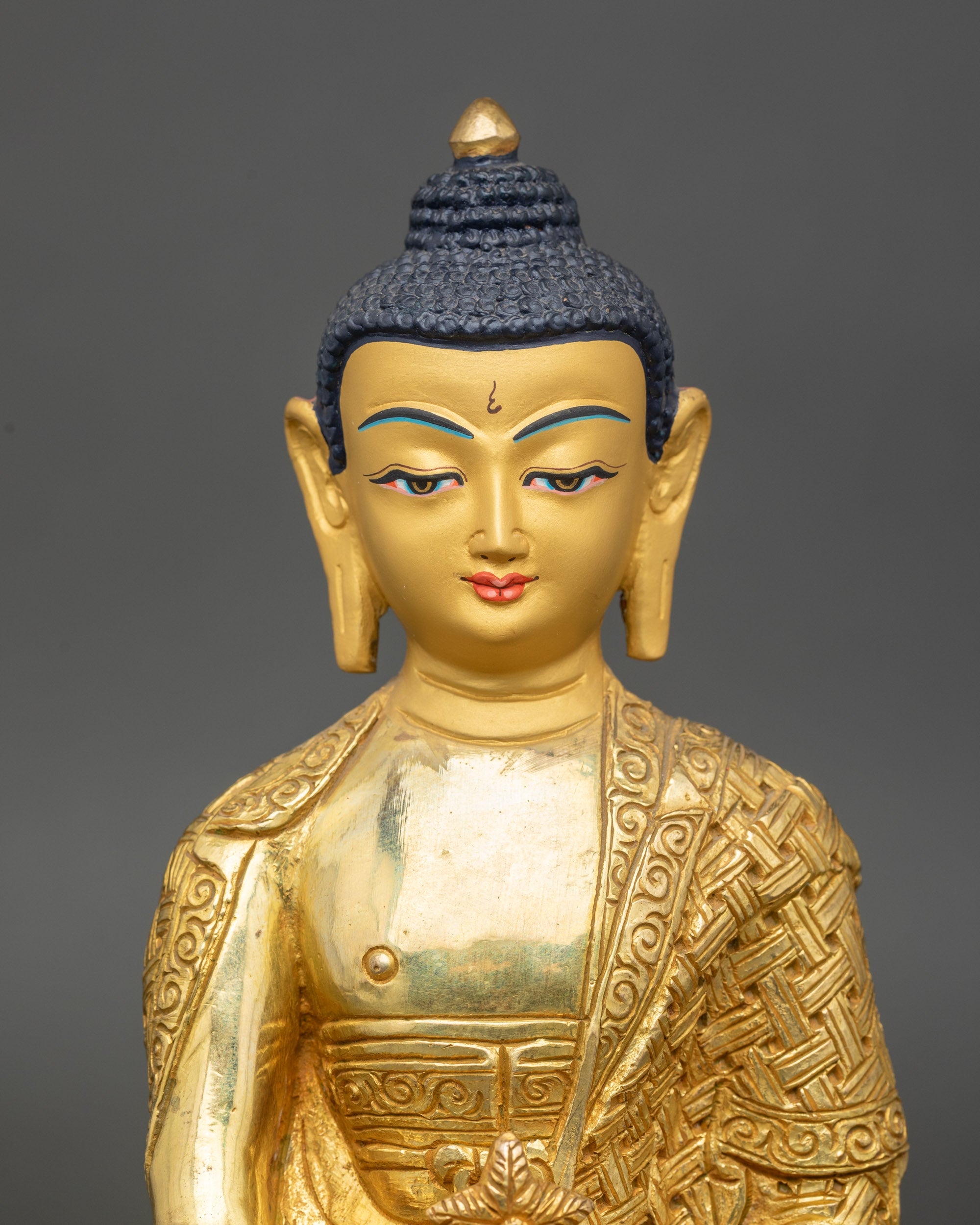 Regular close-up of Medicine Buddha statue showing serene gold-painted face and lotus seat