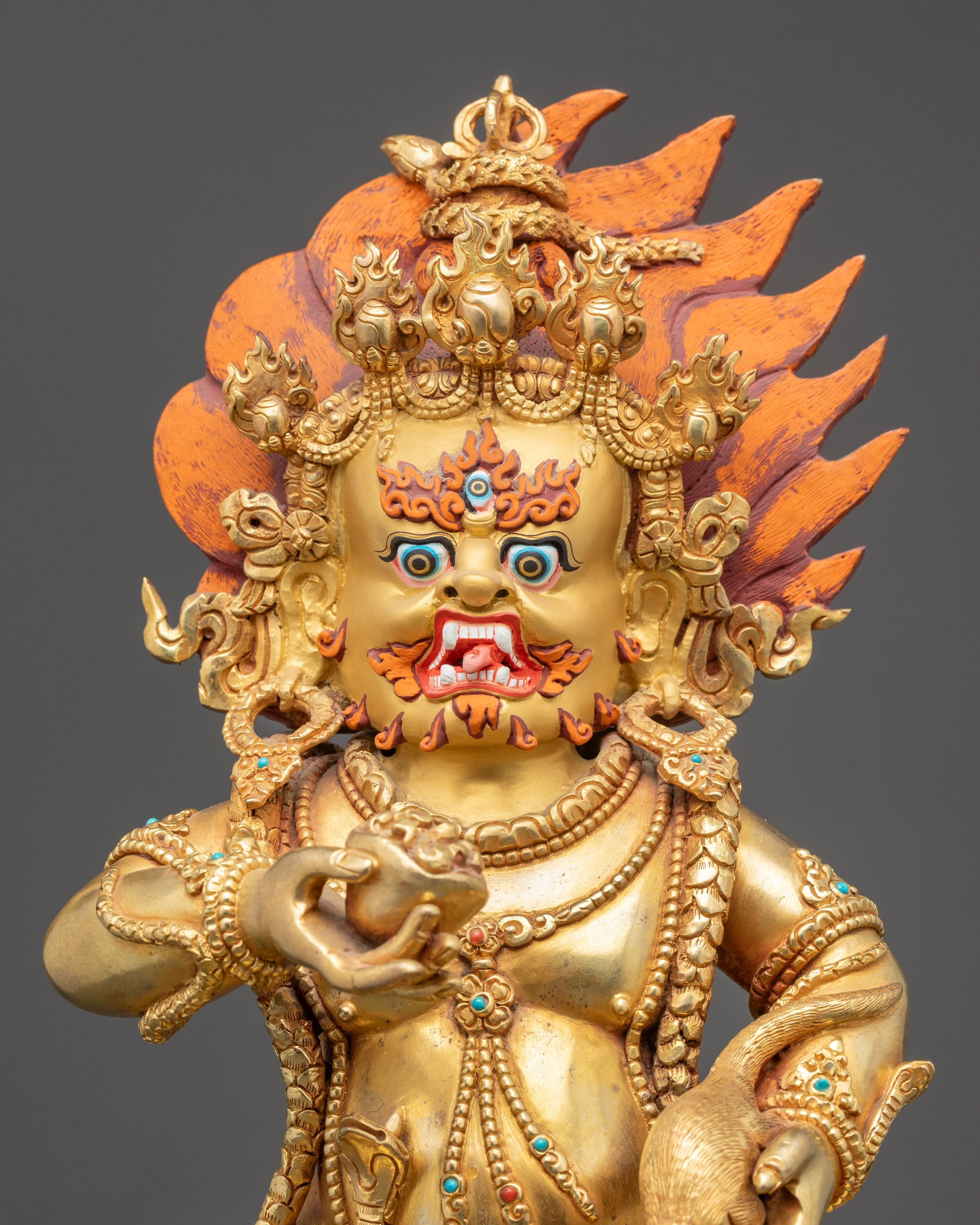 Regular close up Black Dzambhala idol showing wrathful gold-gilded face and third eye