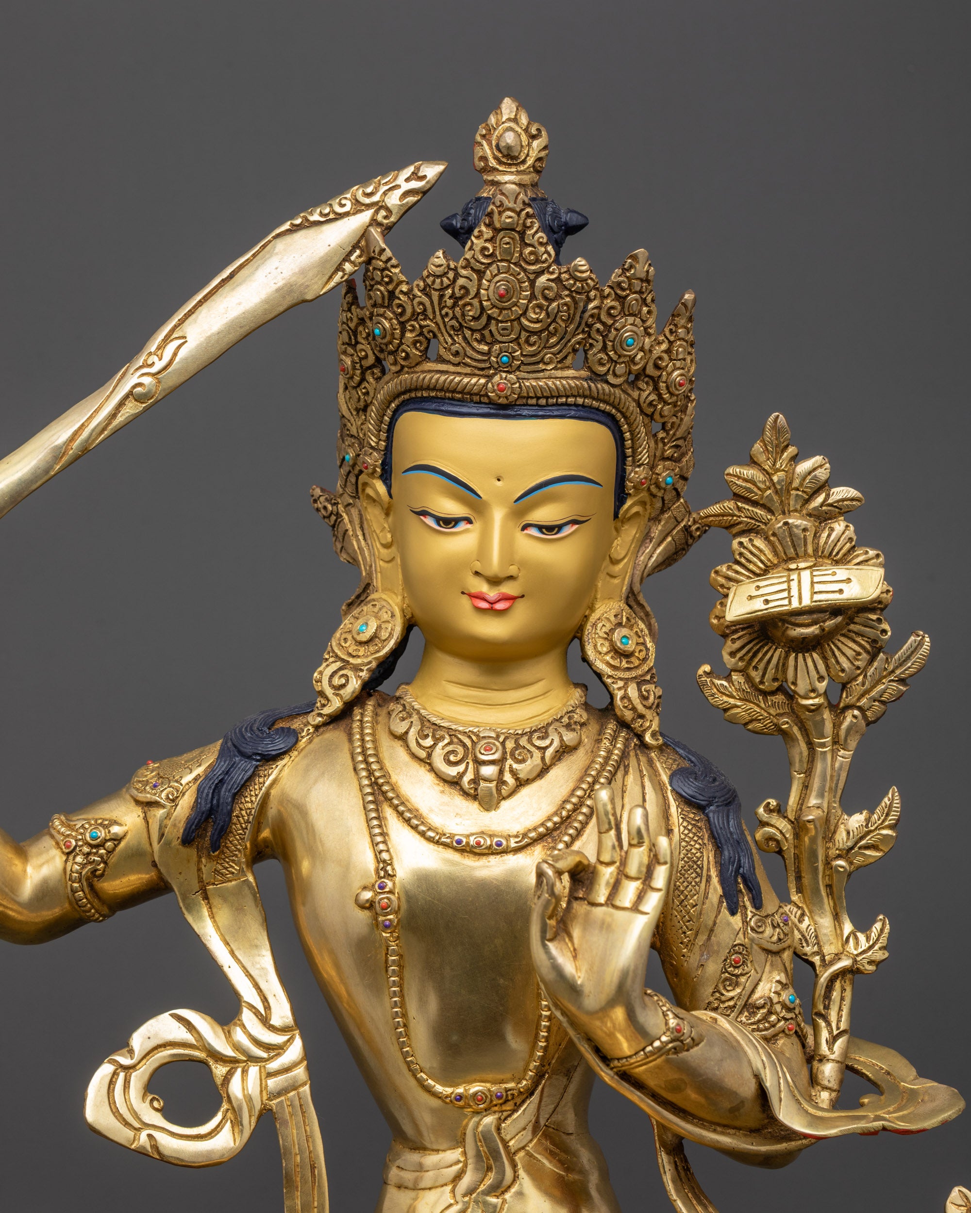 Regular close up Manjushri sculpture showing gold-gilded serene face and intricate robes