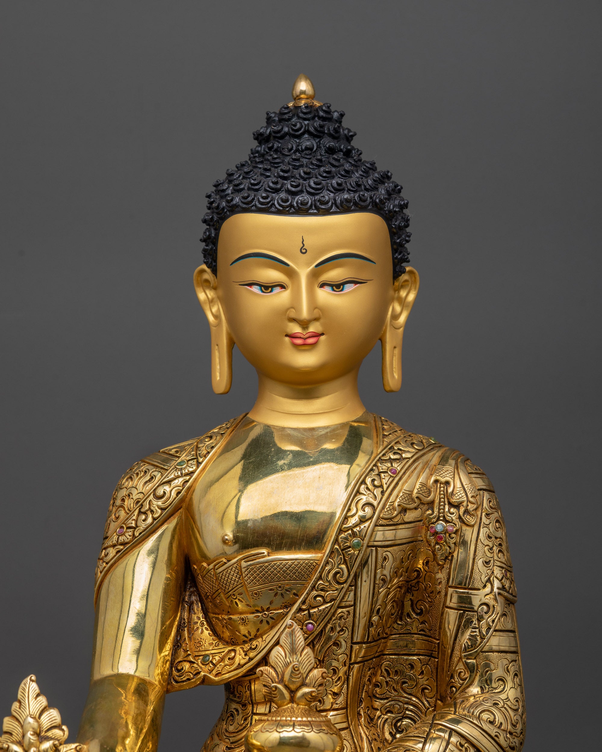 Regular close up Medicine Buddha statue showing serene gold-gilded face and robes