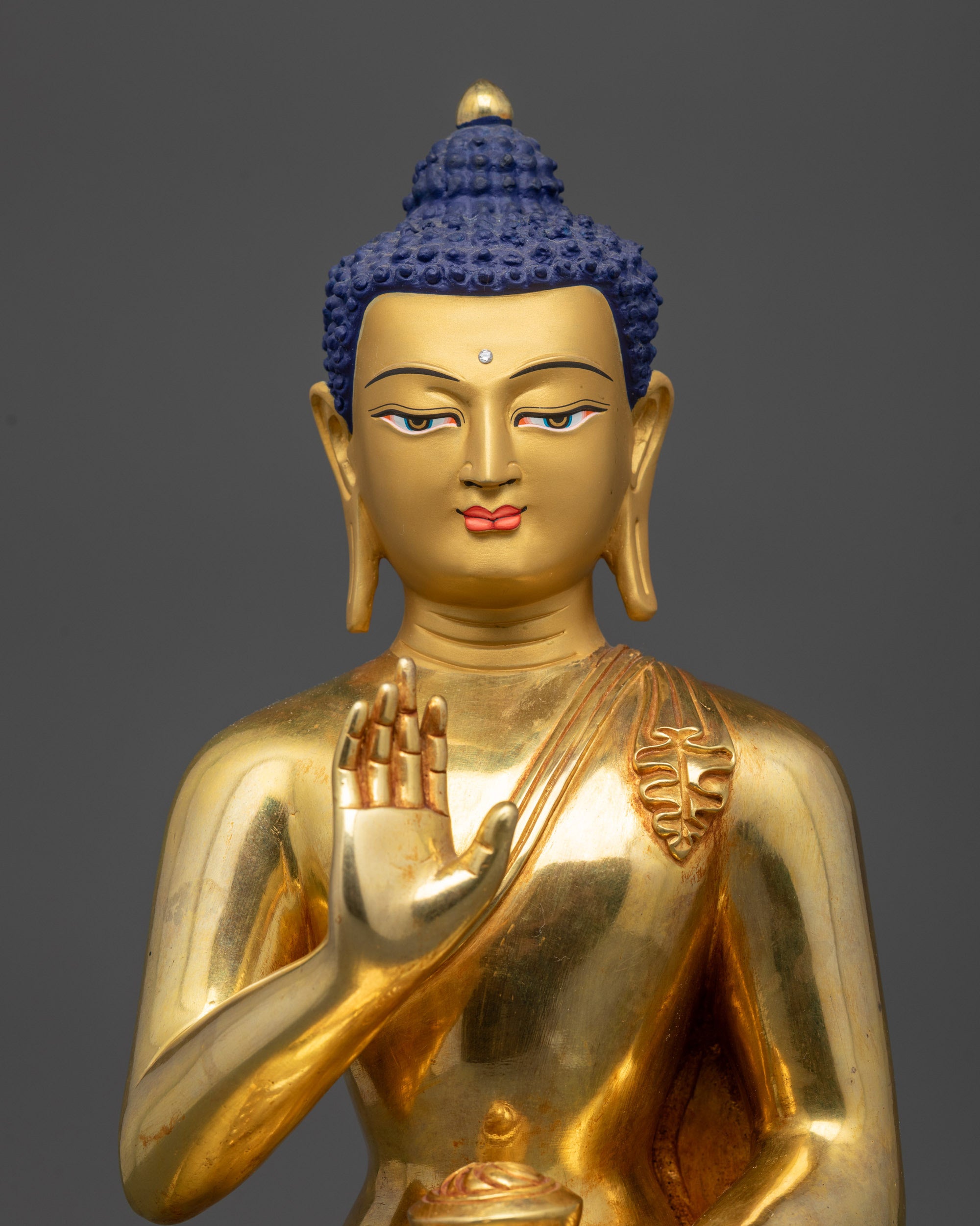 Regular close up of Amoghasiddhi Buddha statue showing serene expression and polished robe
