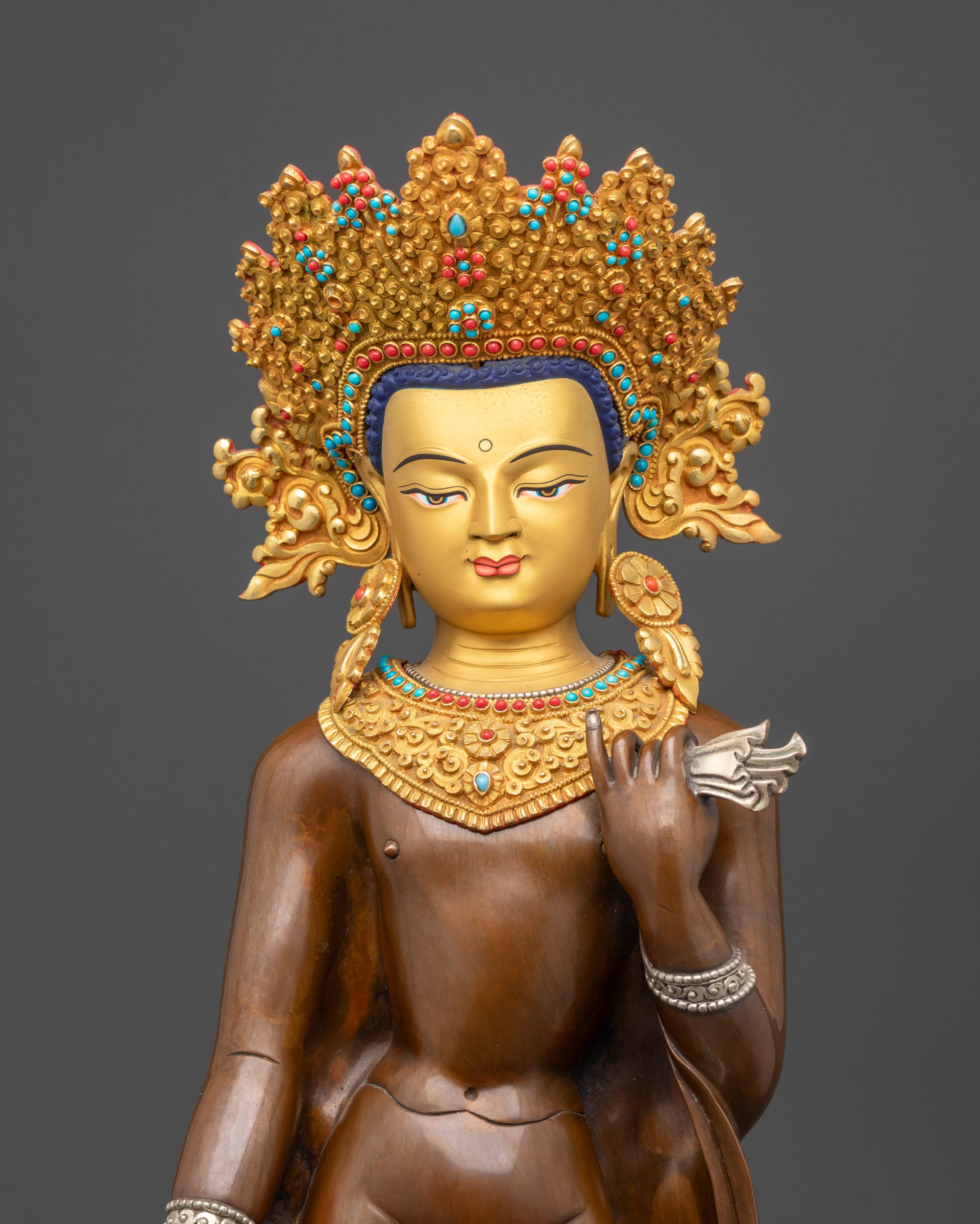 Regular close up of Dipankara Buddha statue showing silver-plated robes and jewelry