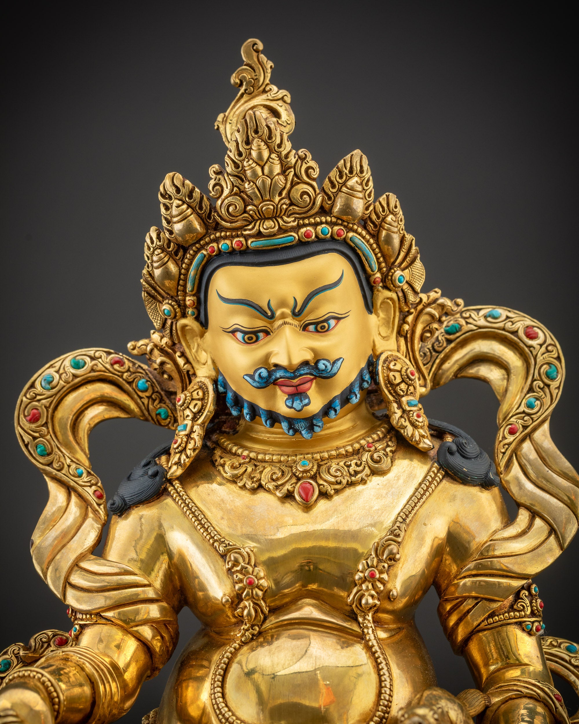 Regular close up of Dzambhala statue face highlighting gold-gilded features and fierce expression