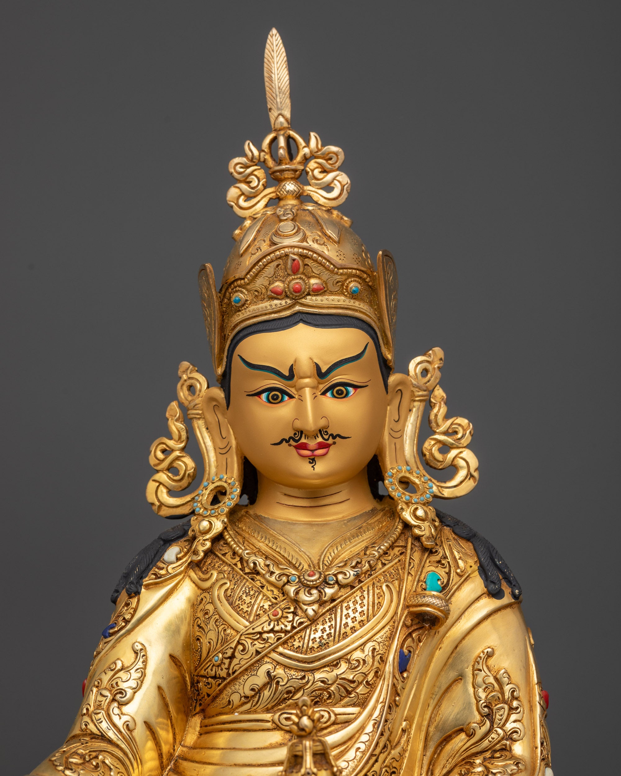Regular close up of Guru Padmasambhava statue showing gold-gilded face and robes