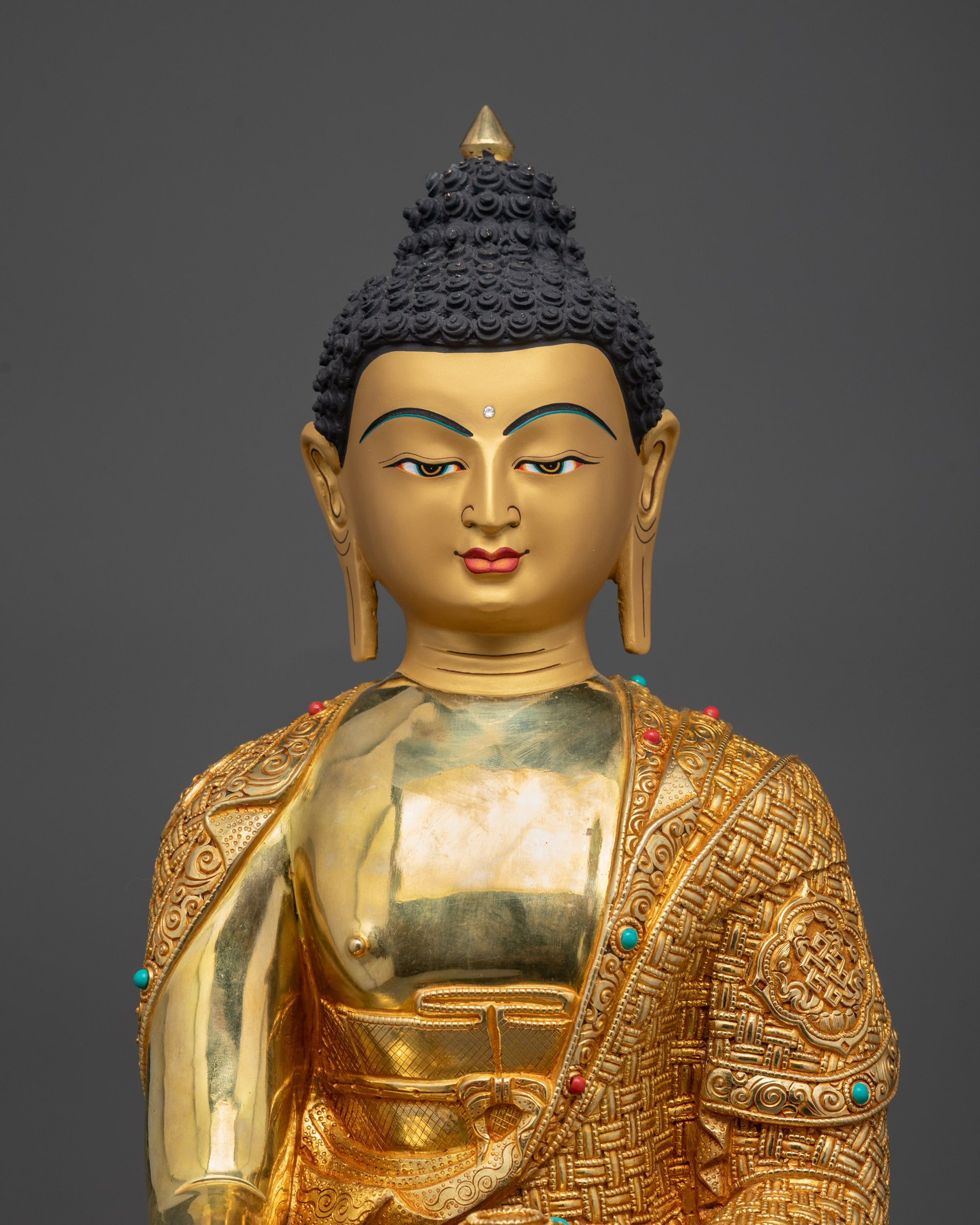 Regular close up of Shakyamuni Buddha statue showing intricate robe patterns and stones