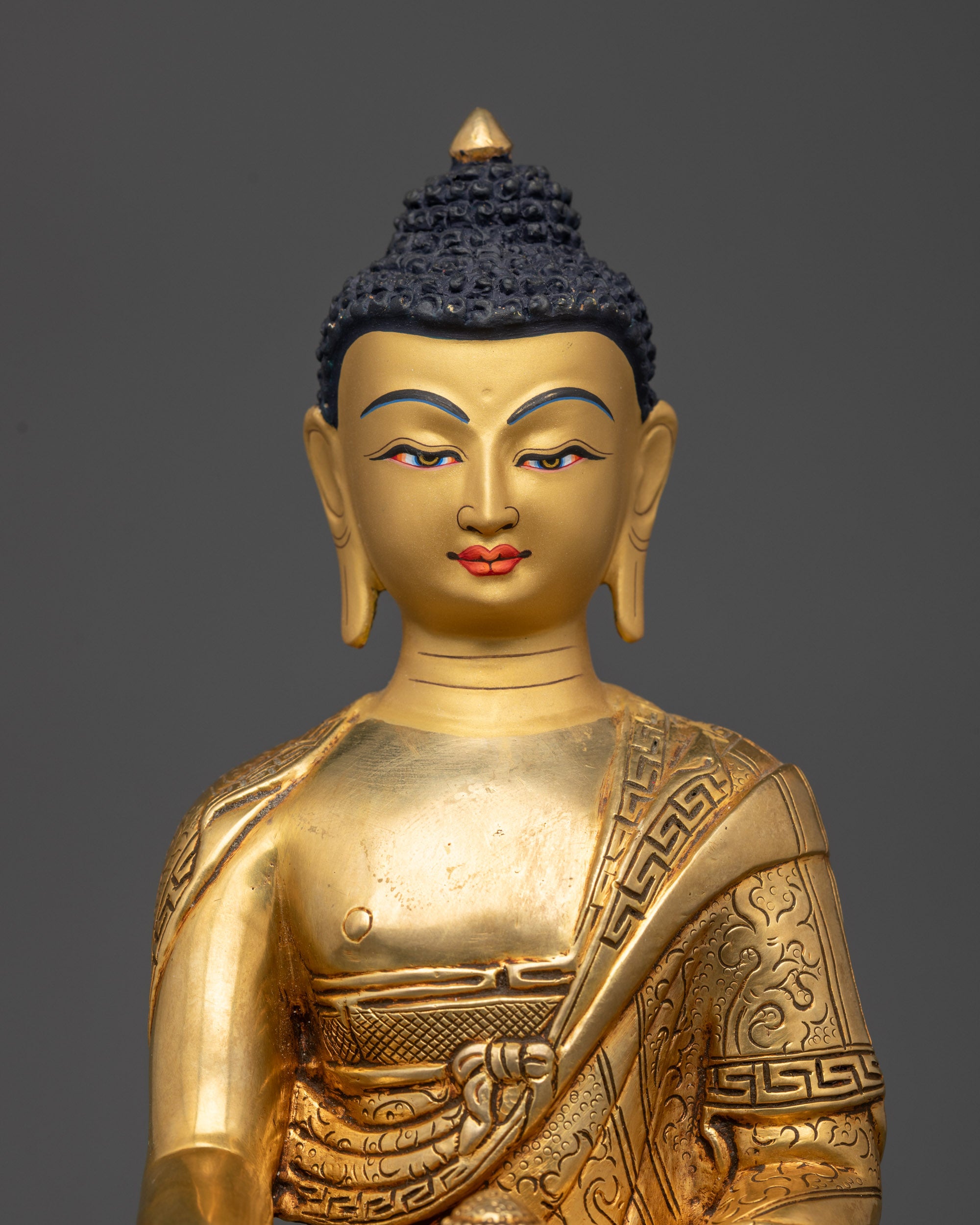 Regular close up of Shakyamuni Buddha statue with intricate robe patterns