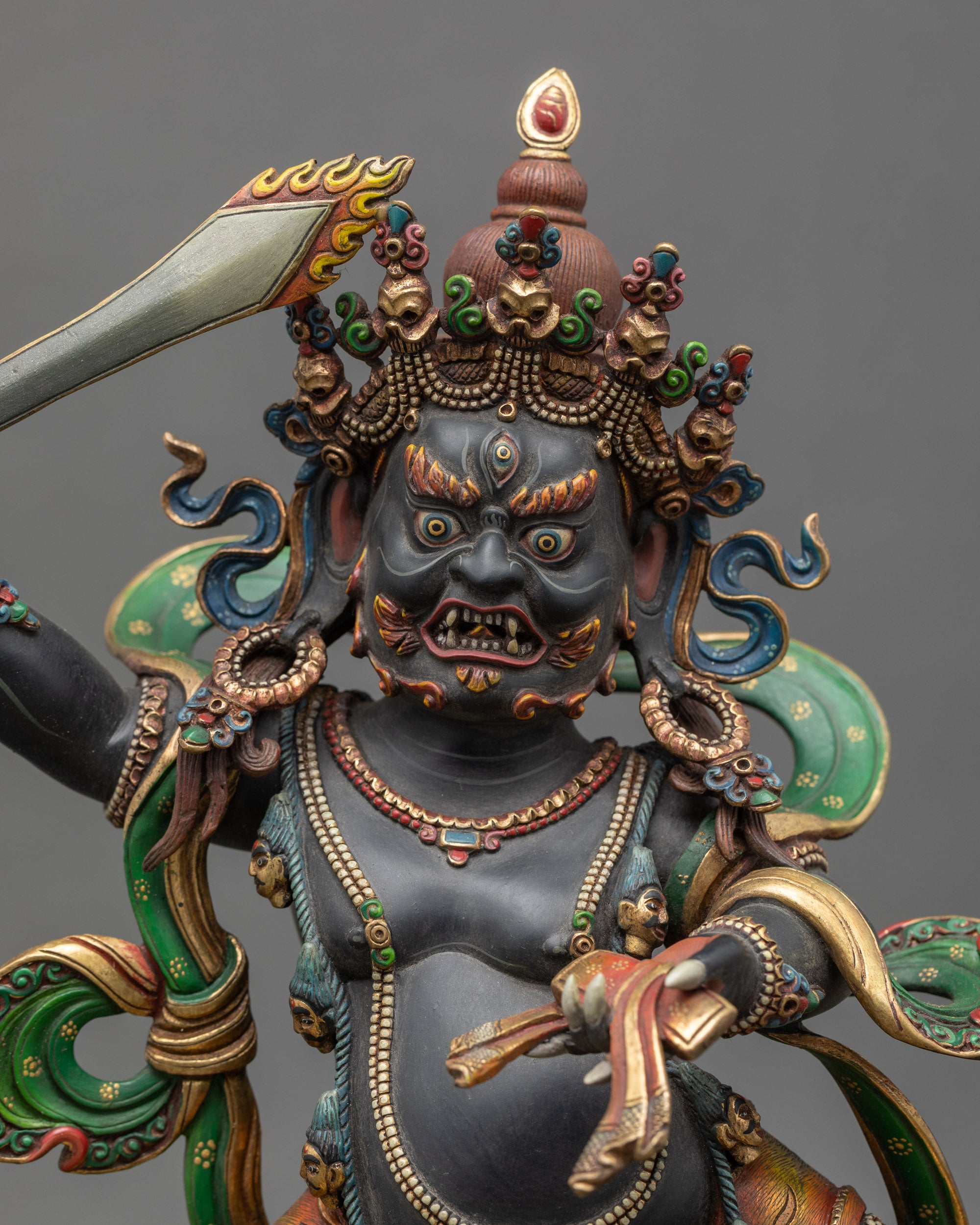Regular close up of wrathful Manjushri statue showing gold-plated finish and vibrant colors