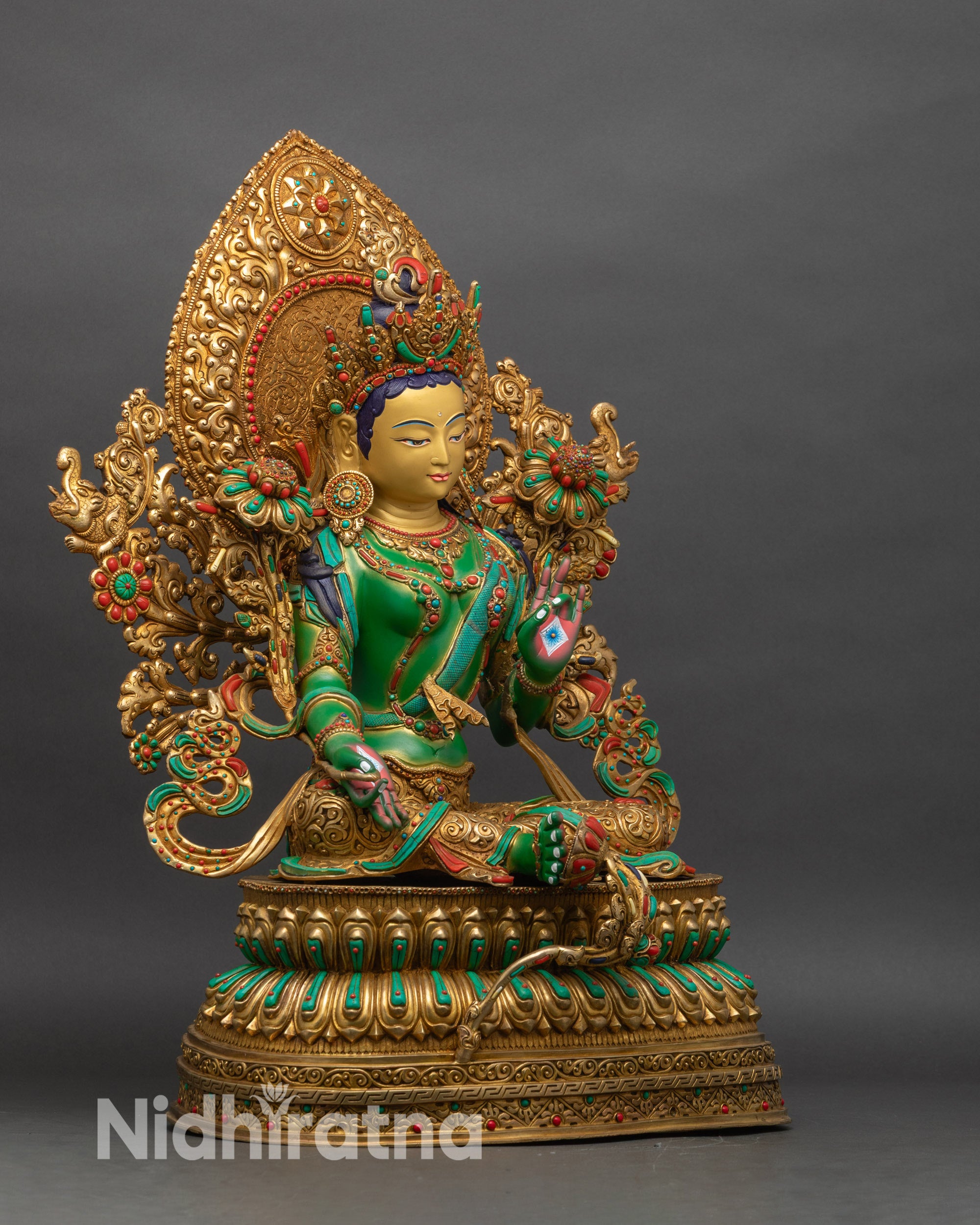 Right profile of Green Tara statue, seated on lotus throne with blue utpala flowers