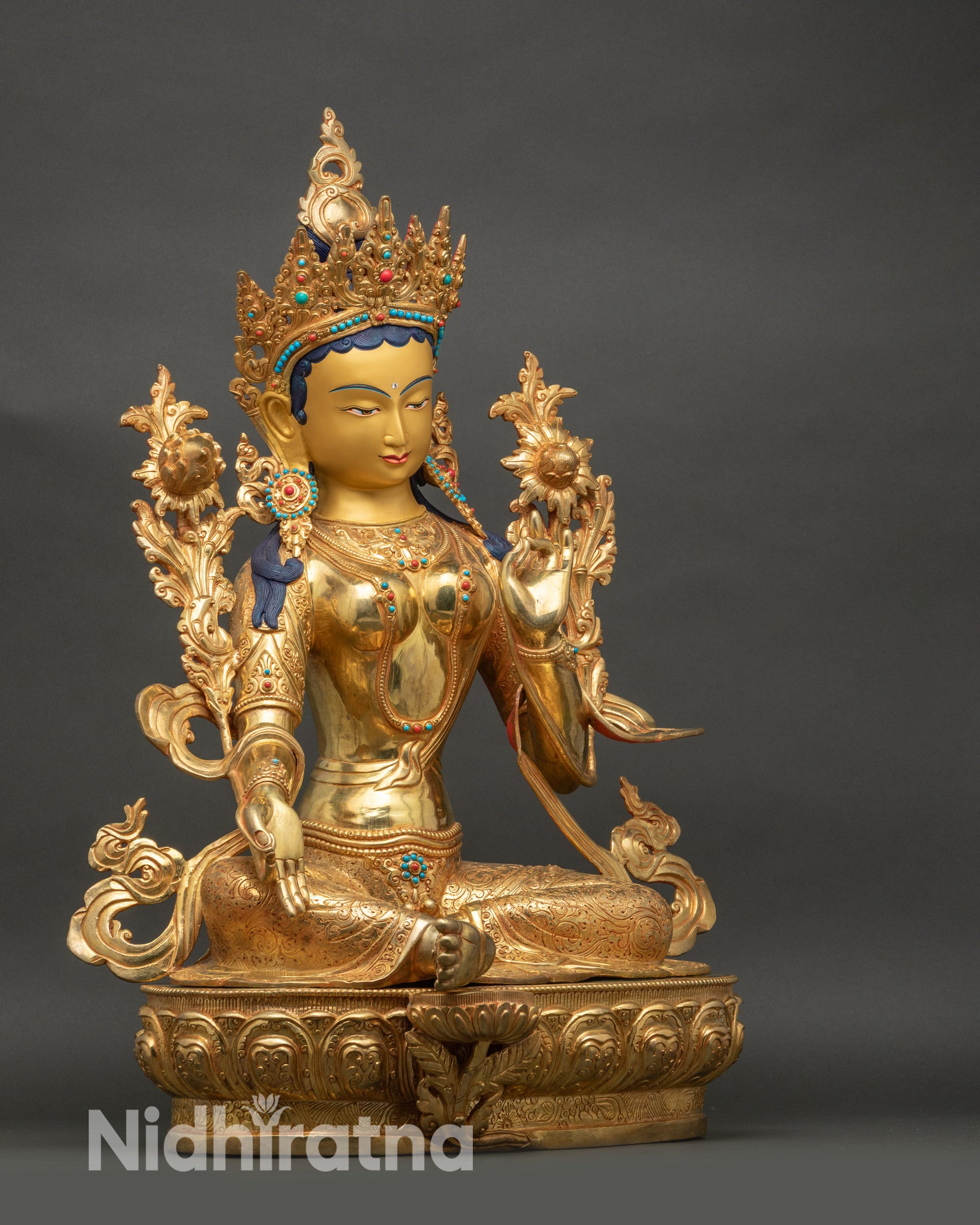 Right side view of Green Tara statue seated in royal ease on lotus throne