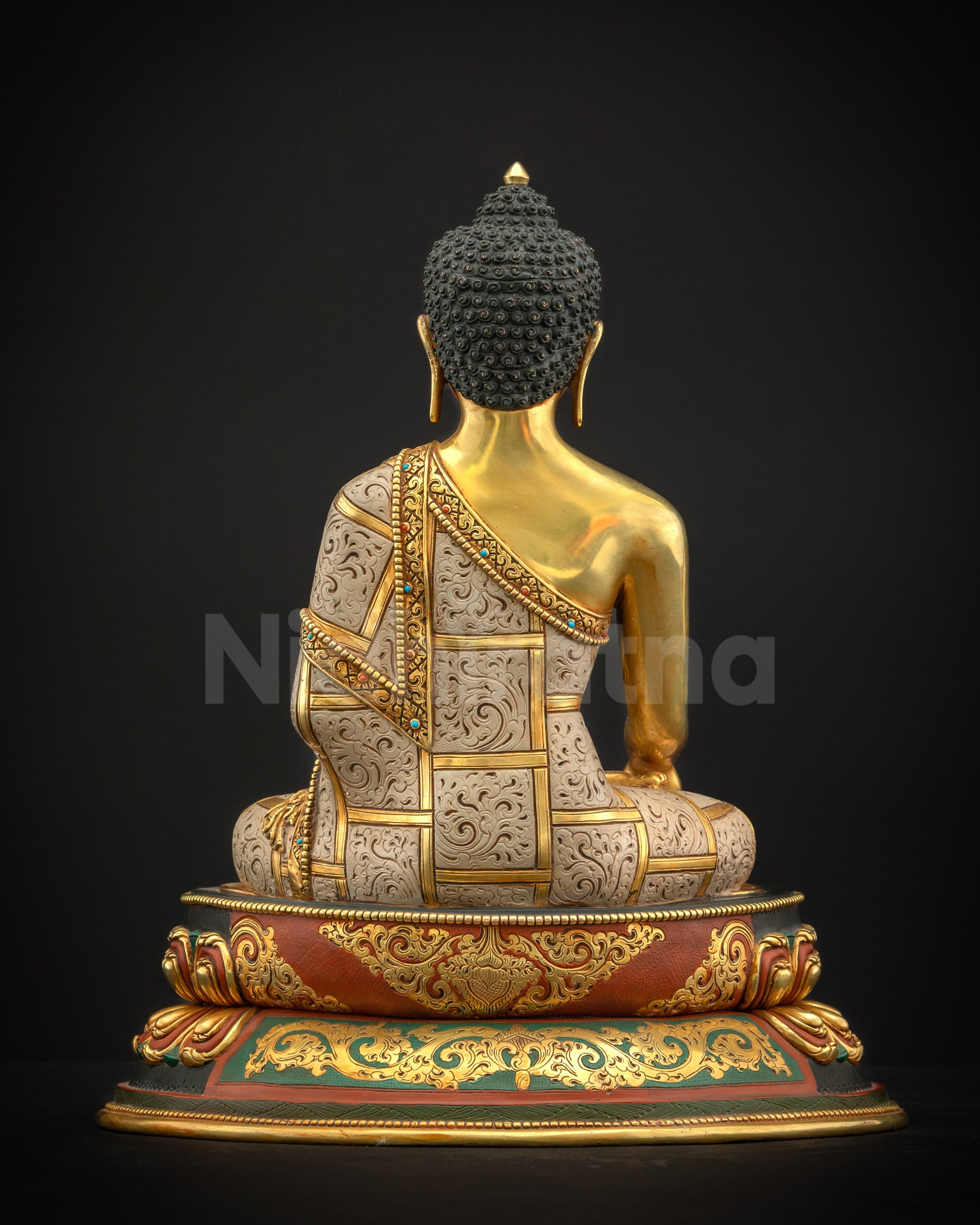 Back view of Shakyamuni Buddha statue showing finely carved robe details, lotus pedestal