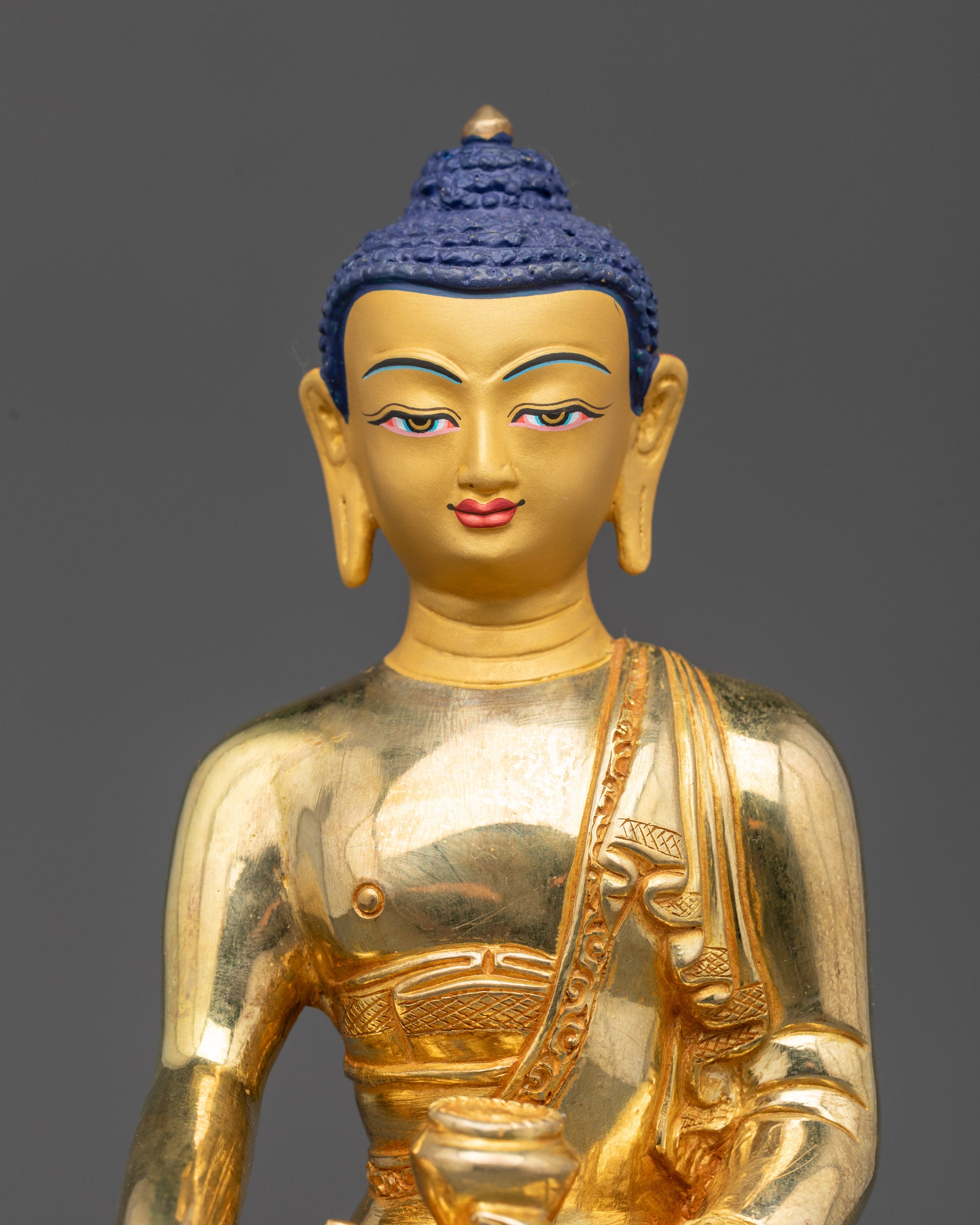 Shakyamuni Buddha statue close up gold-gilded serene face and patra bowl