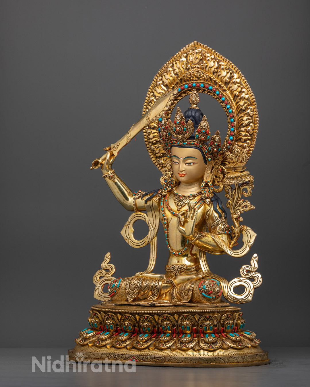 Side angle of Bodhisattva Manjushri statue showing sword, flower, and flowing robe