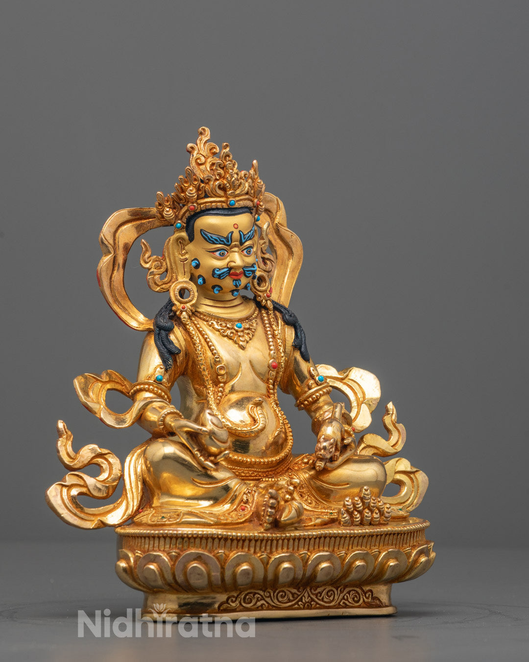 Side angle of Dzambhala sculpture showing royal ease pose on lotus throne with moon disc