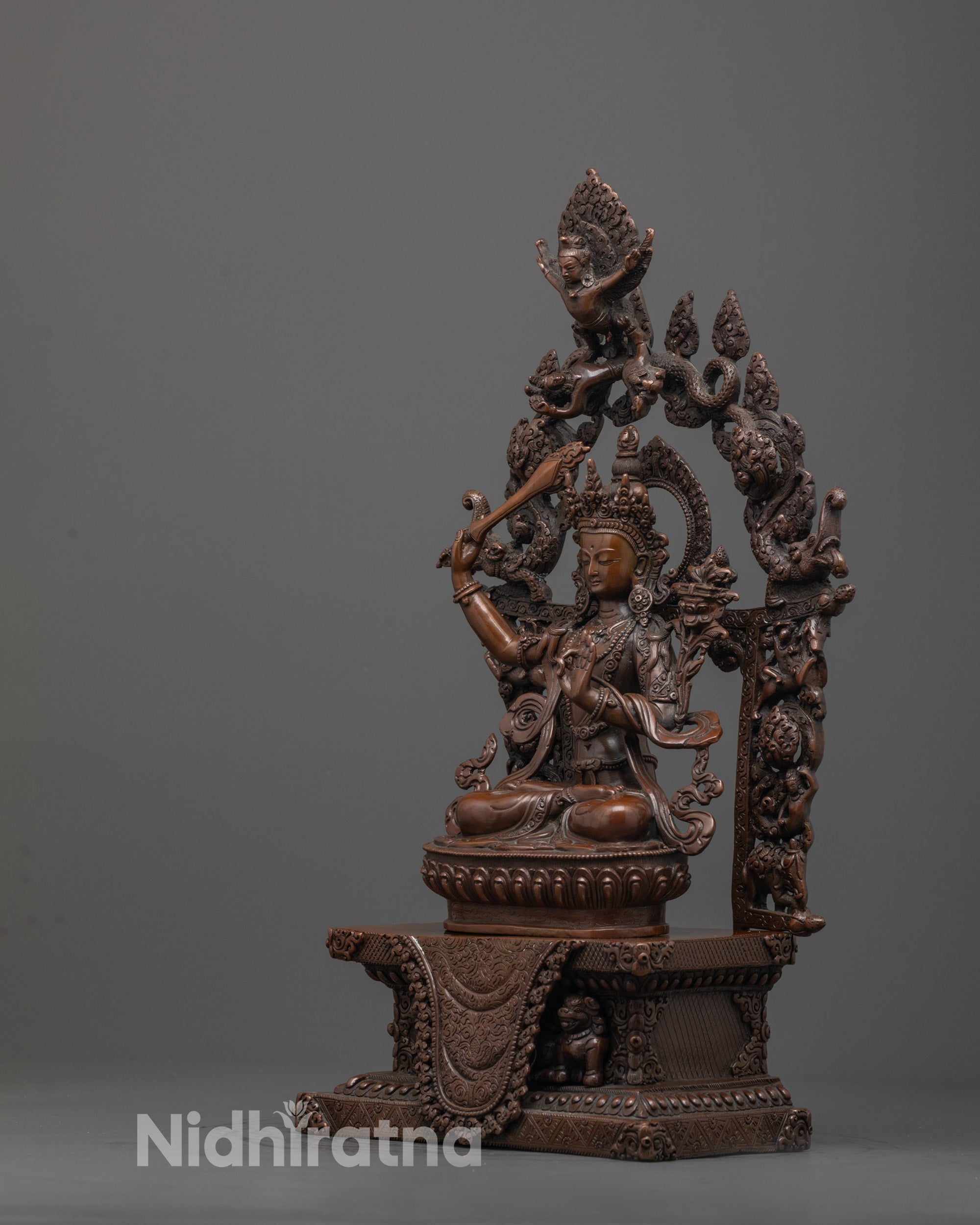 Side angle of Himalayan Manjushri statue showing intricate royal robes and lotus petals
