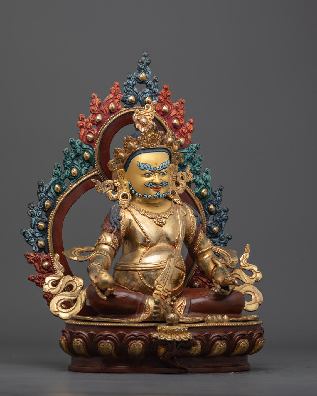 Side angle of Kubera statue - flowing robe, fire-gilded body, sacred Buddhist art