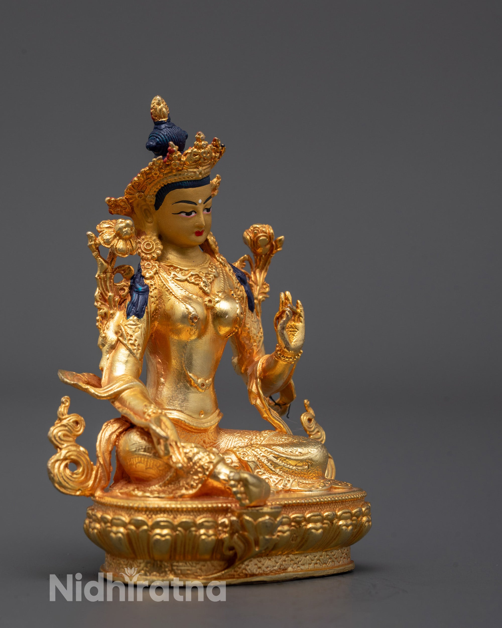 Side angle of Tibetan Green Tara statue seated in royal ease pose holding utpala flower
