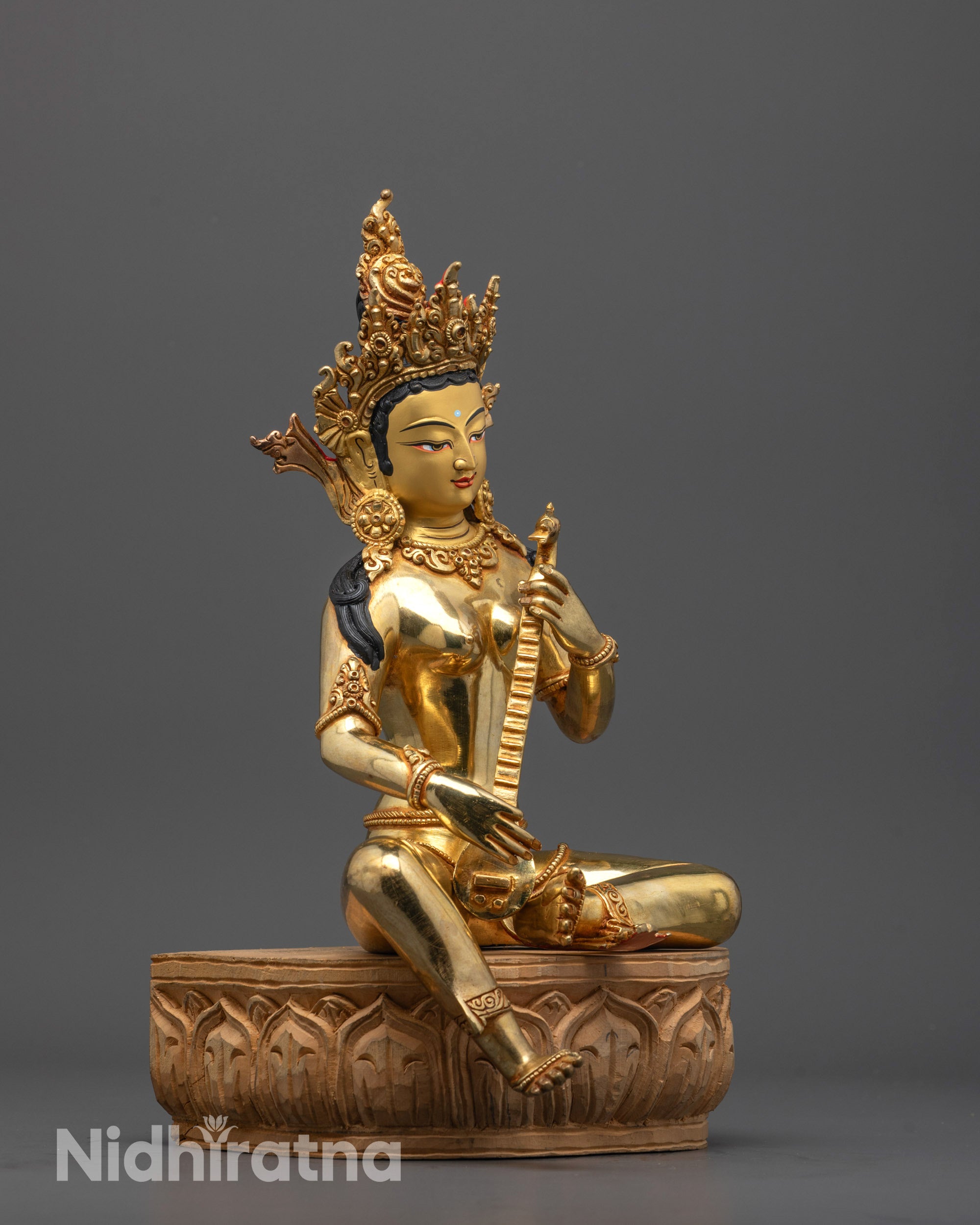 Side angle of handcrafted Saraswati statue showing copper base and polished wooden platform