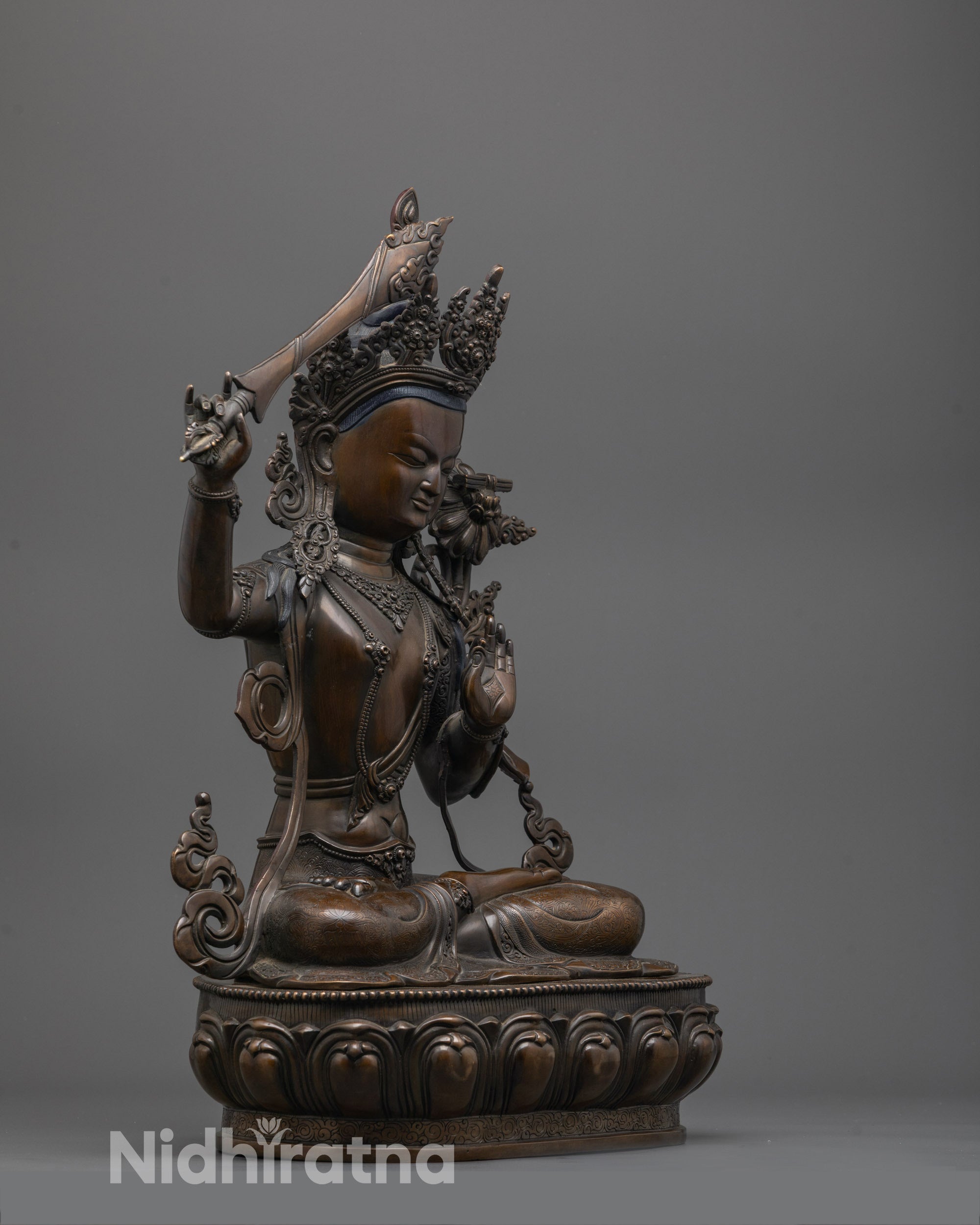 Side angle of oxidized copper Manjushri statue showing polished finish and fine details