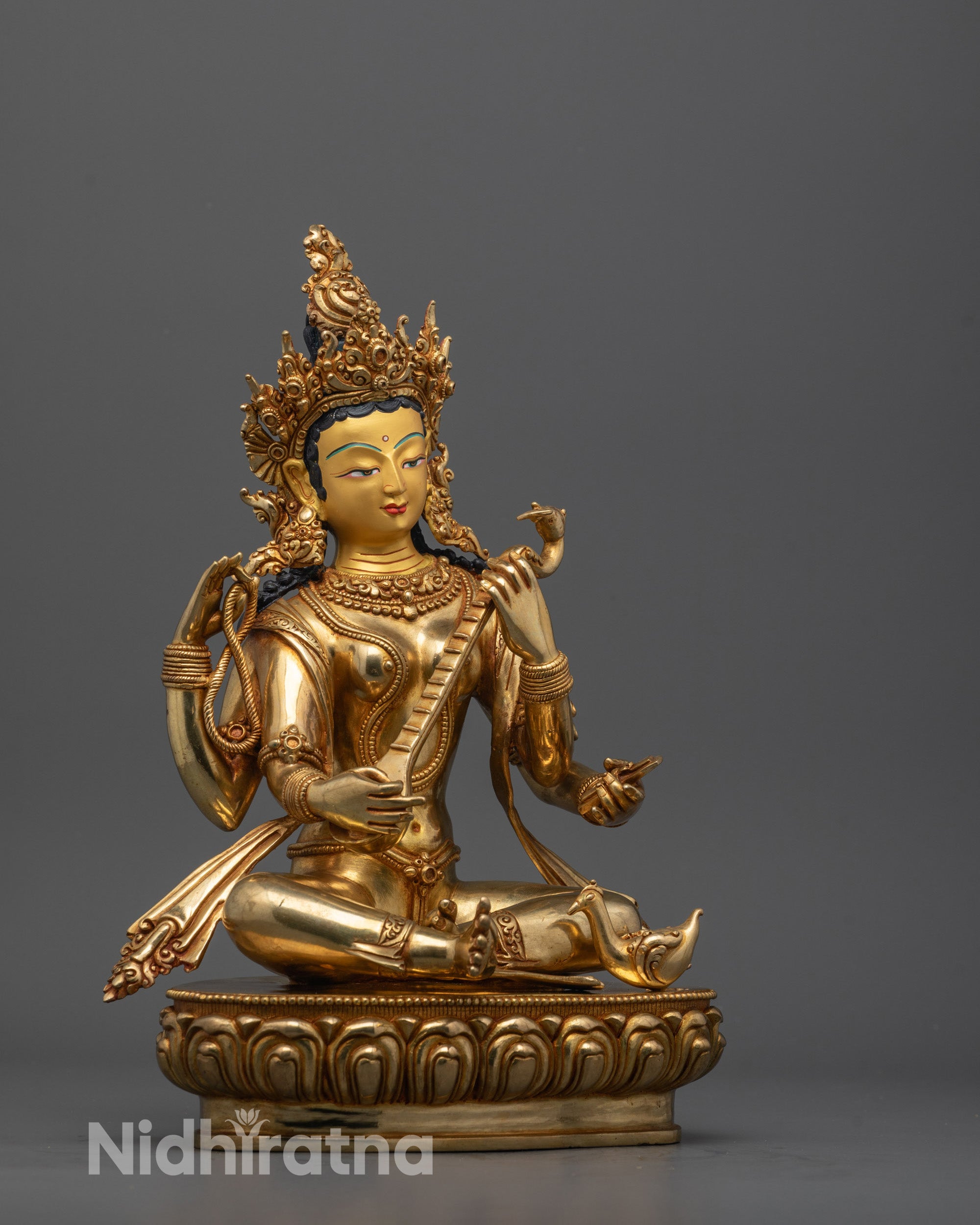 Side angle showing intricate carvings on flowing garments and peacock mayura at her feet.