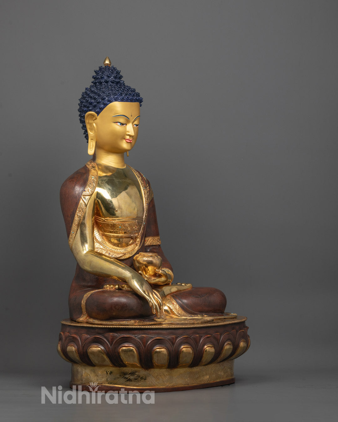Side angle showing partially gold fire-gilded body and copper base of Shakyamuni Buddha sculpture