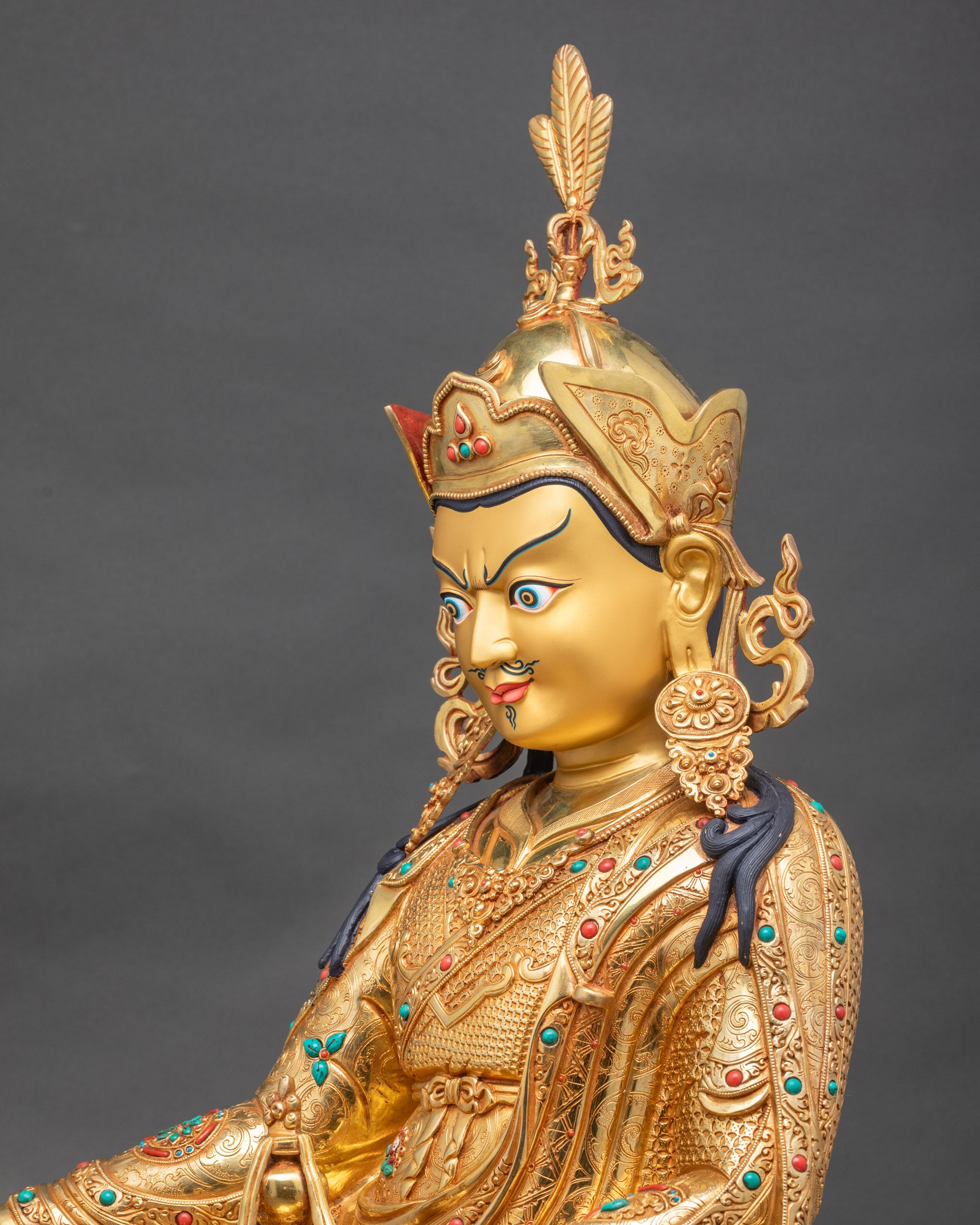 Side close-up of Guru Rinpoche statue highlighting skull cup and Dorje with trident