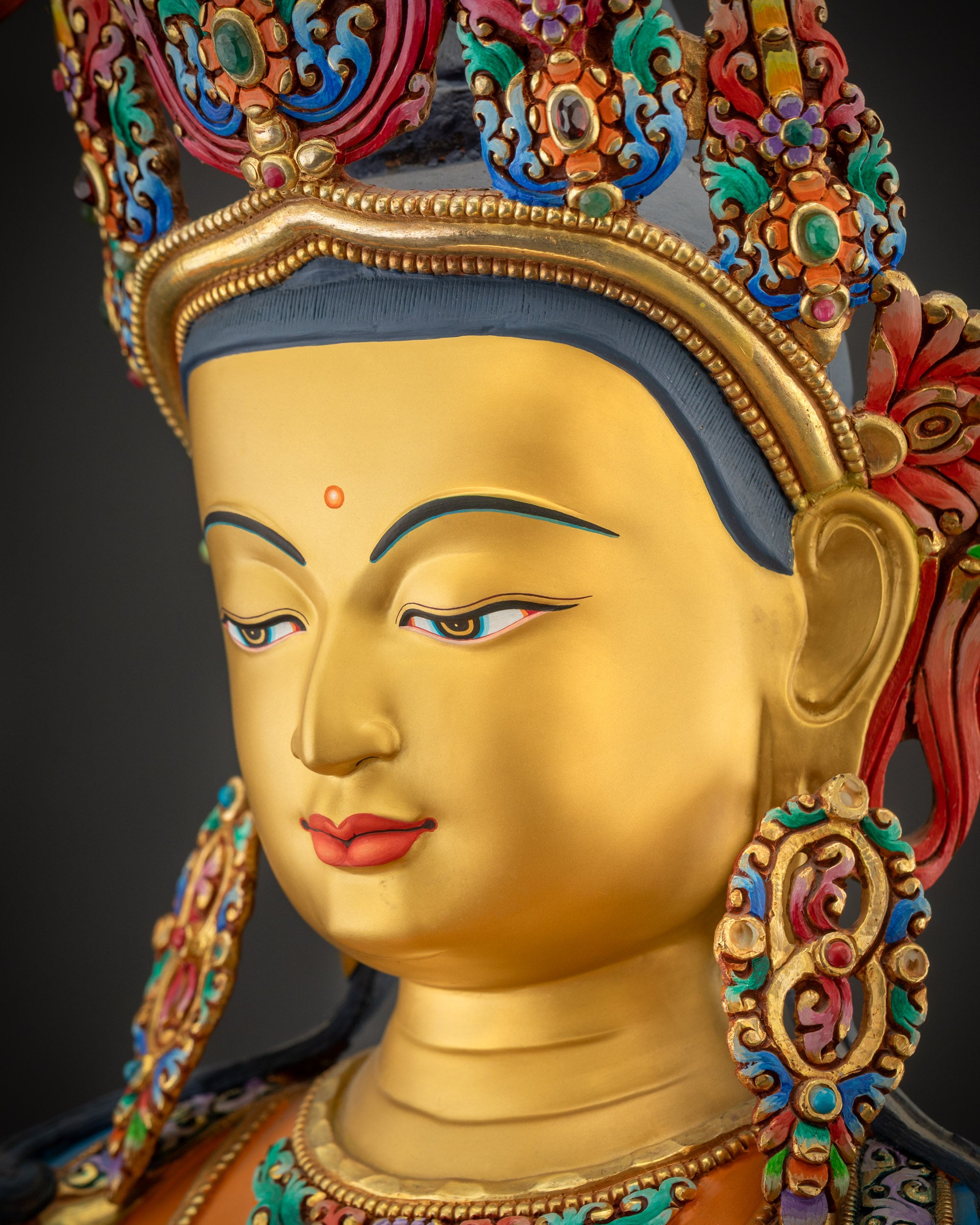 Side close-up of Manjushri statue face showing serene expression and gold-gilded details