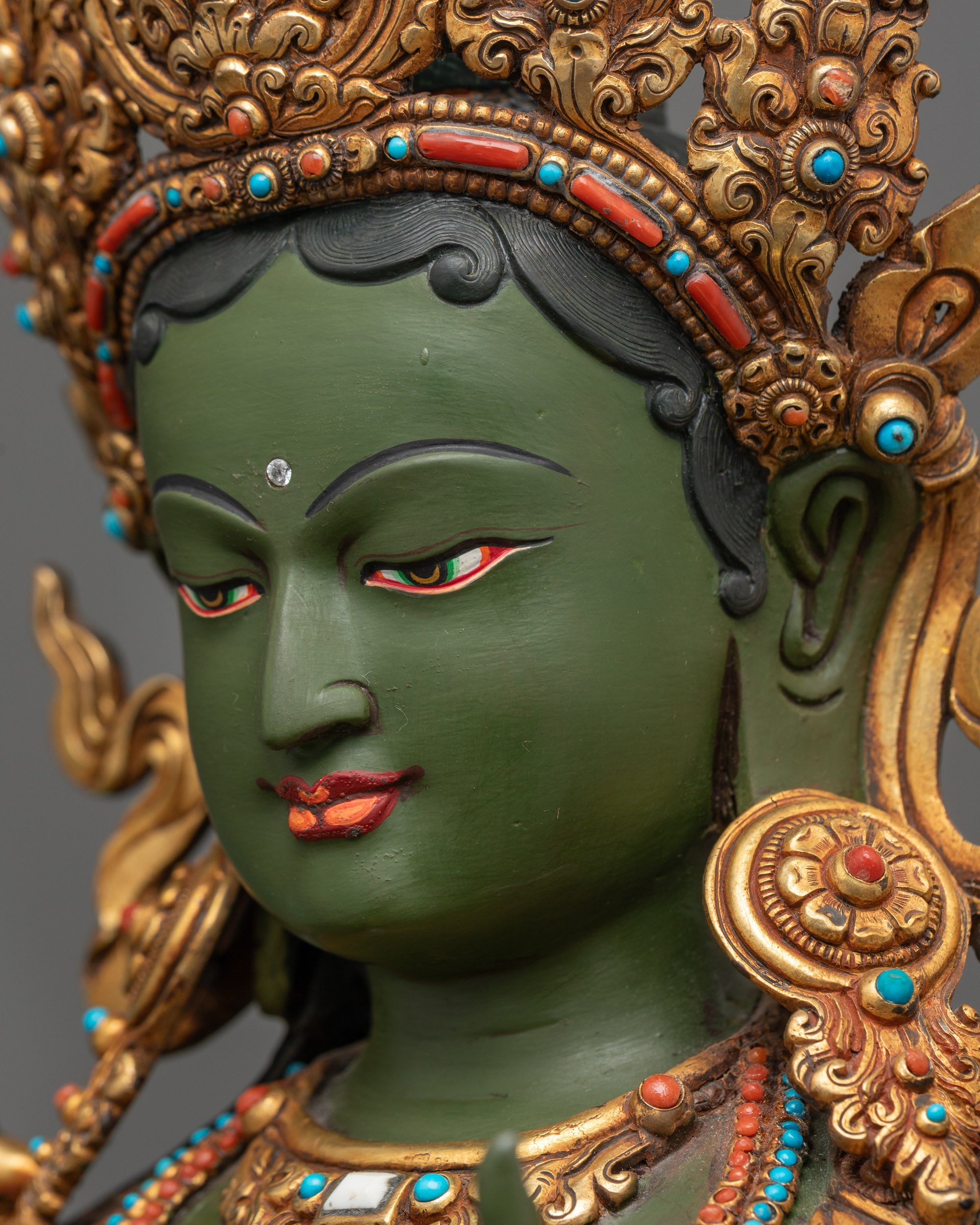 Side close up face of Hand-painted Green Tara sculpture showing intricate carvings