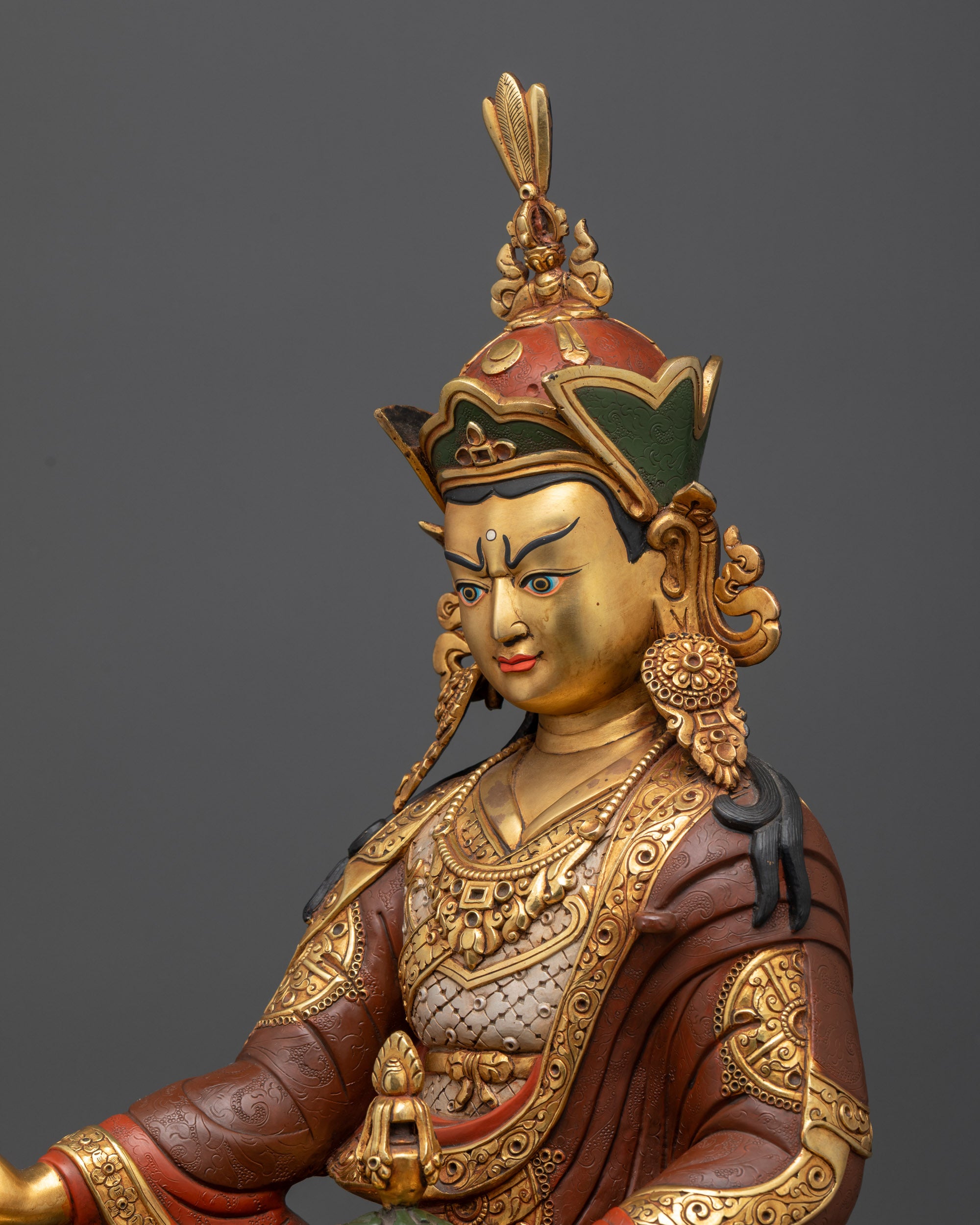 Side close up of Guru Rinpoche face with lotus crown, intricate carvings, and gold-gilded ornaments