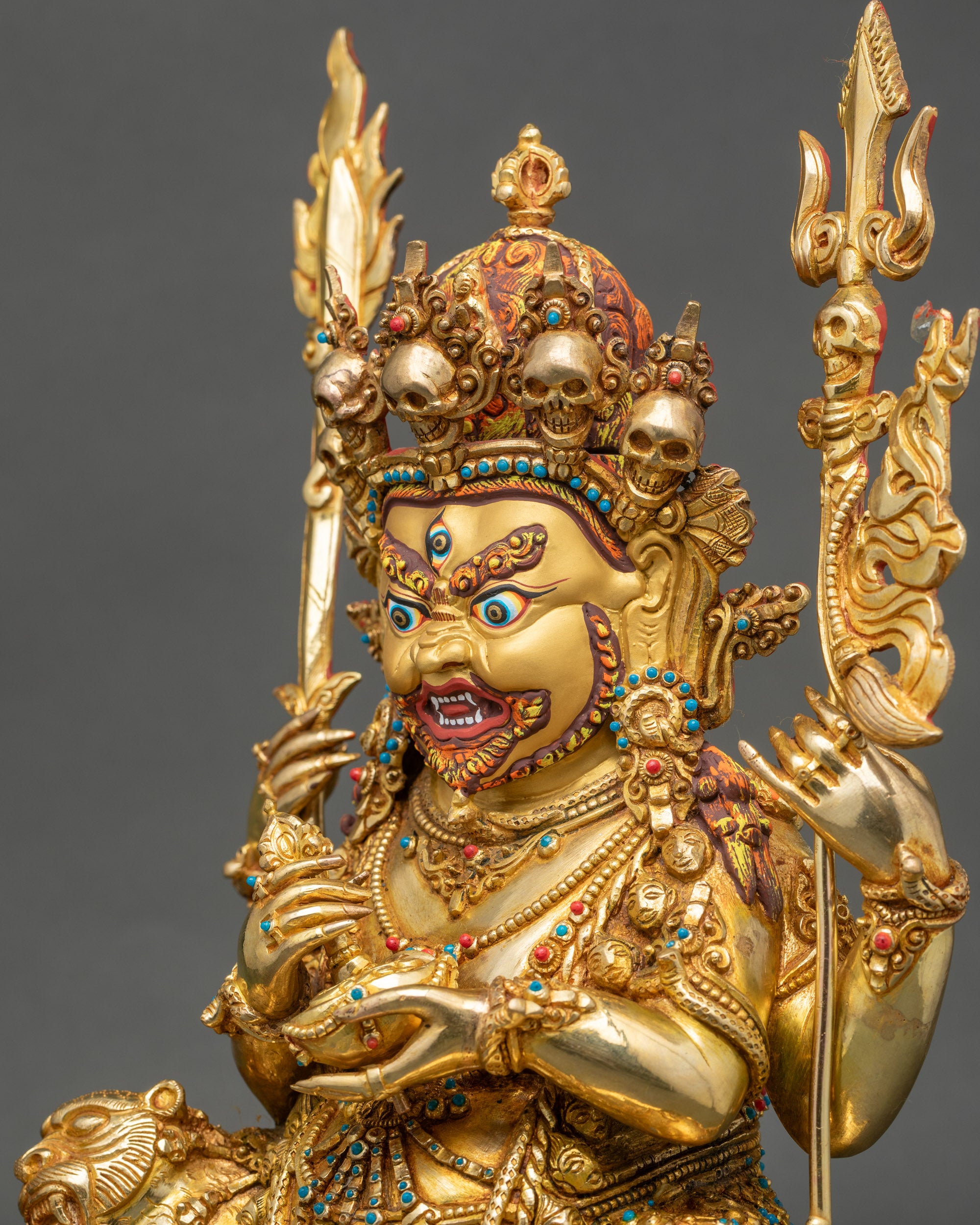 Side detail of Mahakala holding flaming sword and kapala, 24k gold finish.