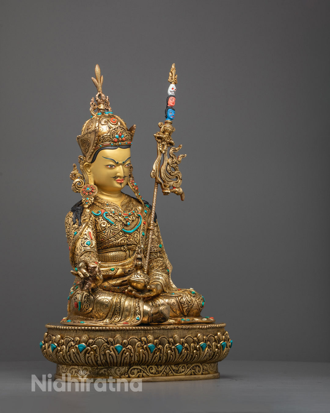 Side profile of Guru Rinpoche statue showing sacred staff
