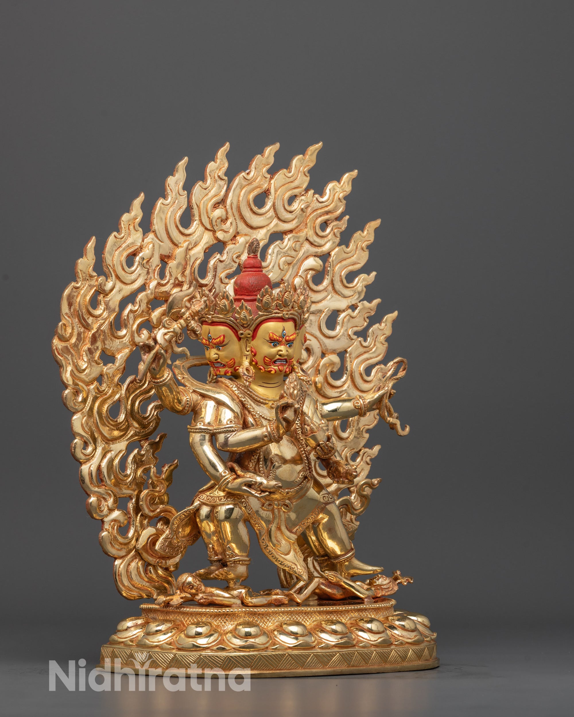 Side profile of Red Dzambhala statue with radiant halo and traditional Himalayan