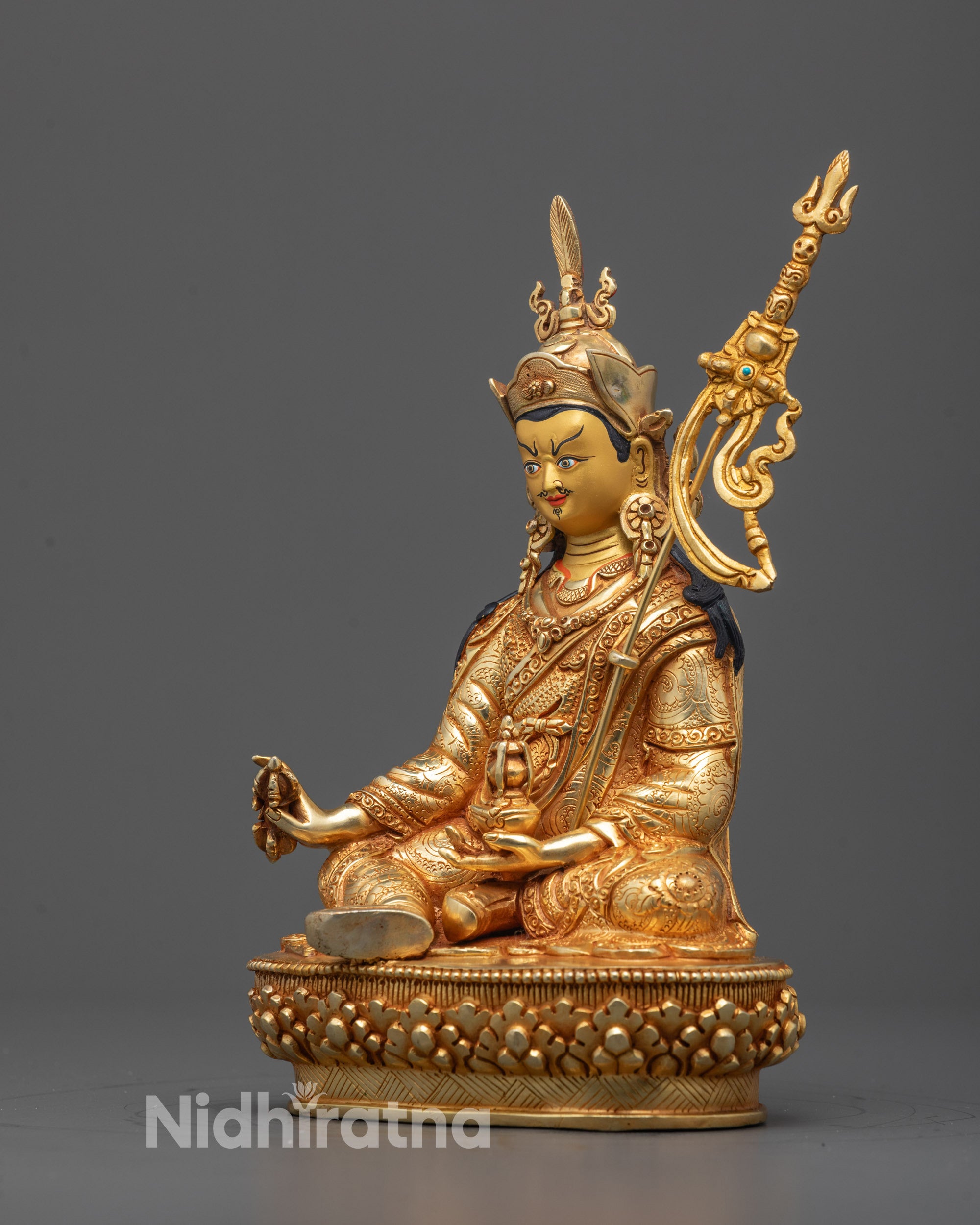 Side profile showing layered robes and staff detail on Guru Rinpoche copper statue