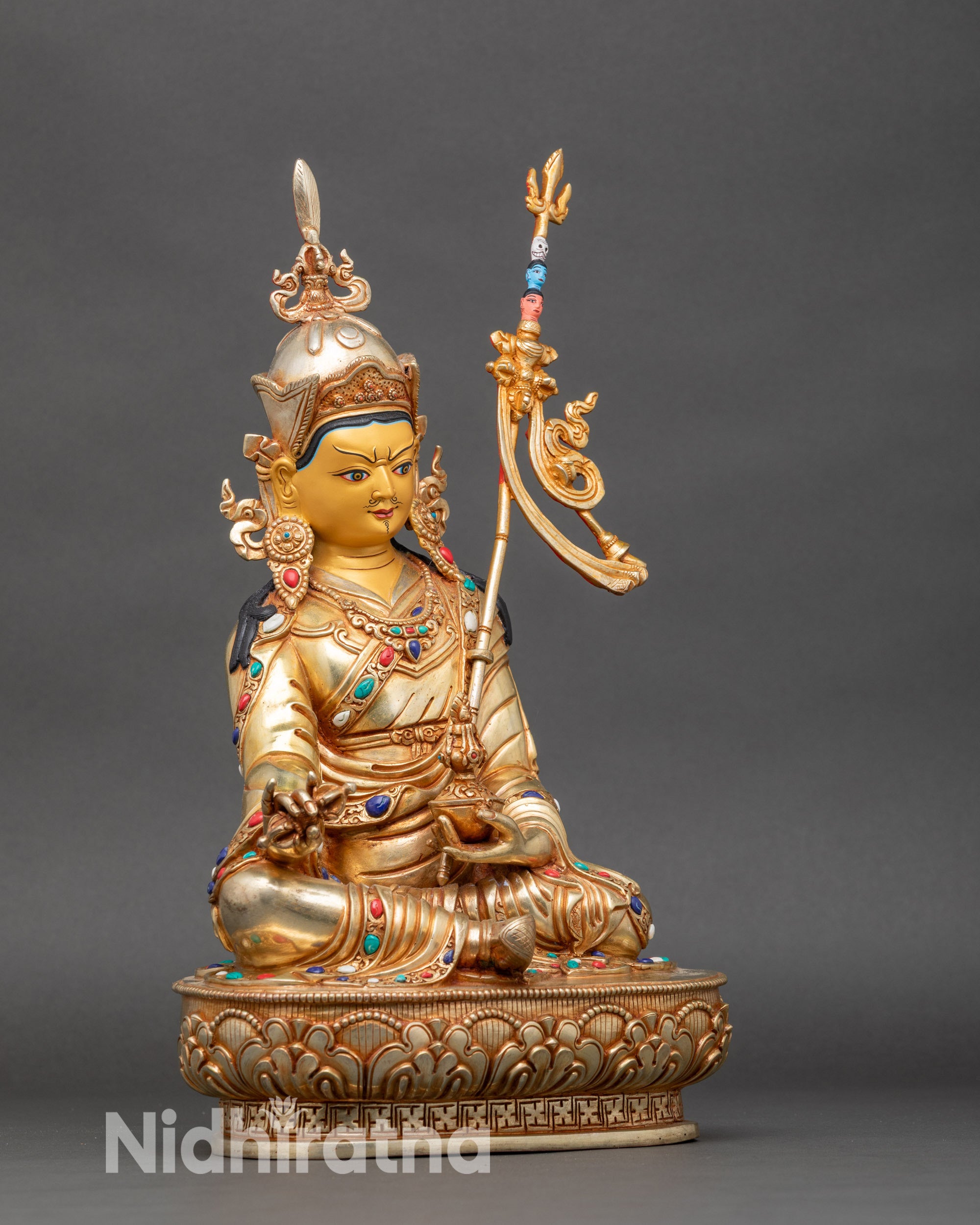 Side view Guru Rinpoche seated on lotus pedestal with gold-painted face and semi-precious stones