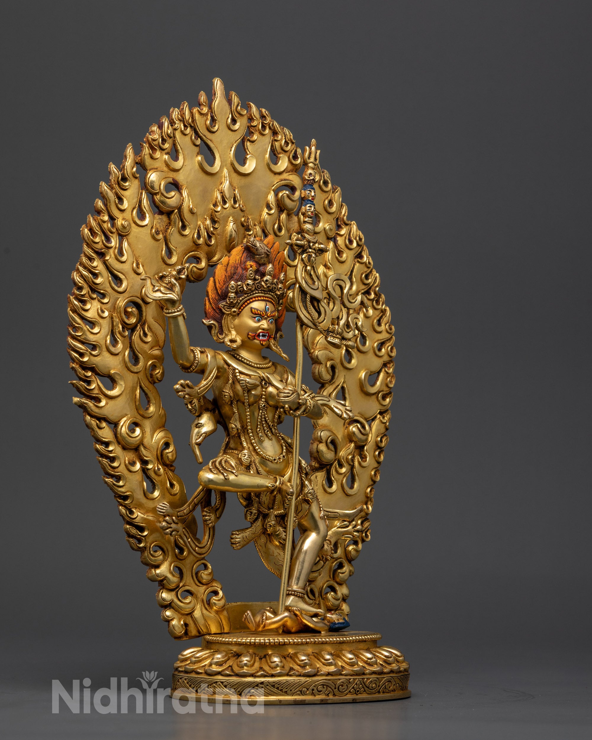 Side view Troma Nagmo holding Kartika knife, skull cup, and trident on lotus seat