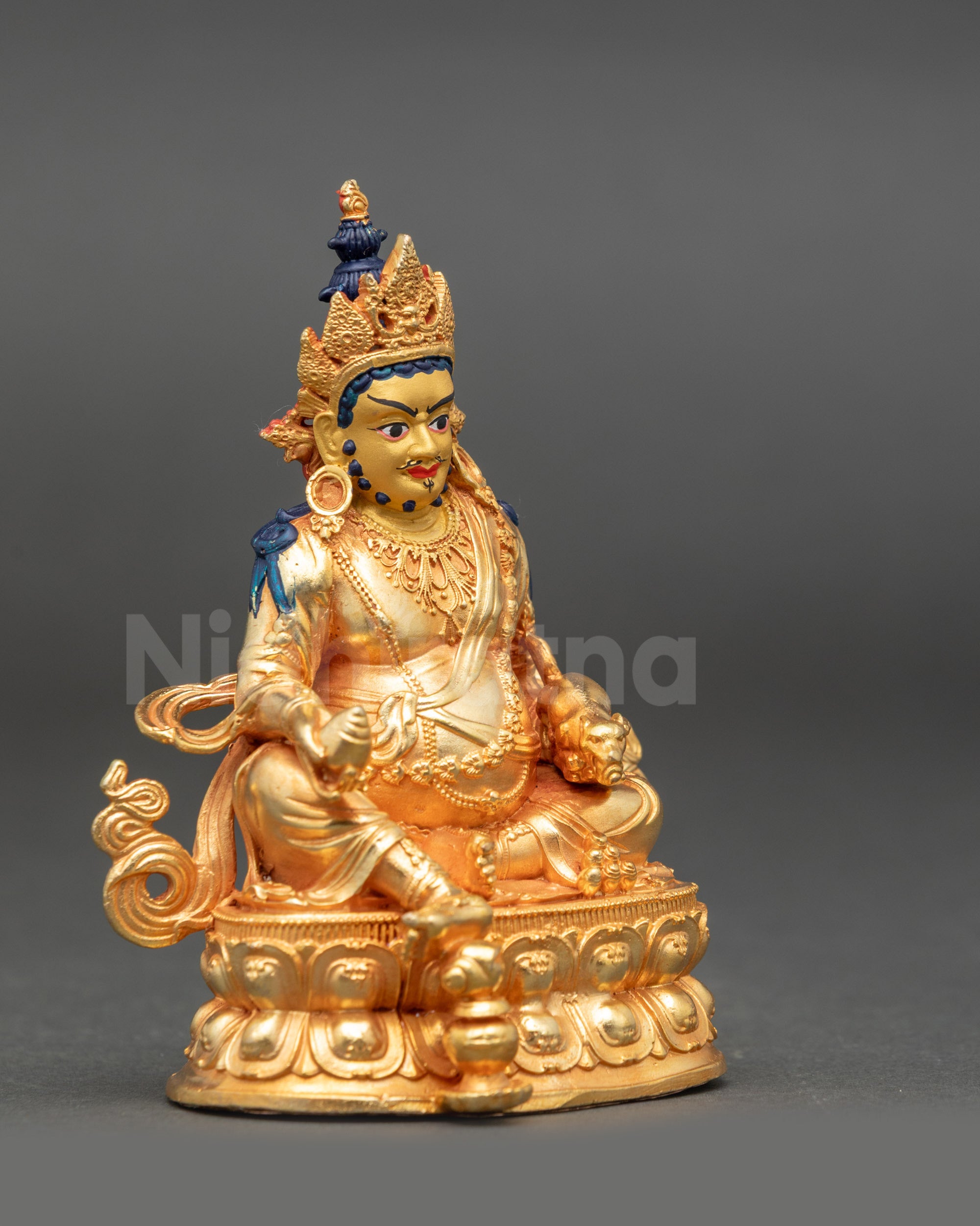 Side view of Dzambhala statue showing snake ornaments, citron fruit, and meditation posture