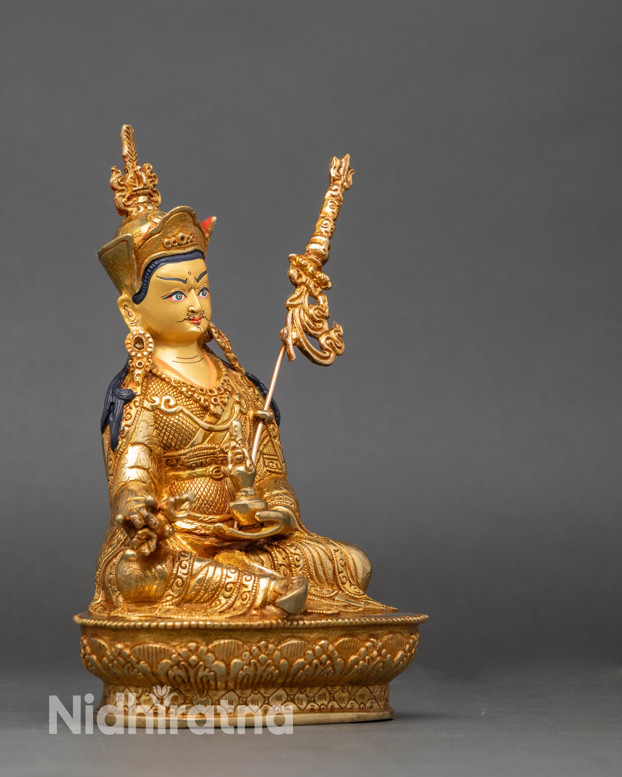 Side view of Guru Rinpoche deity sculpture holding vajra and kalash, lotus throne detail