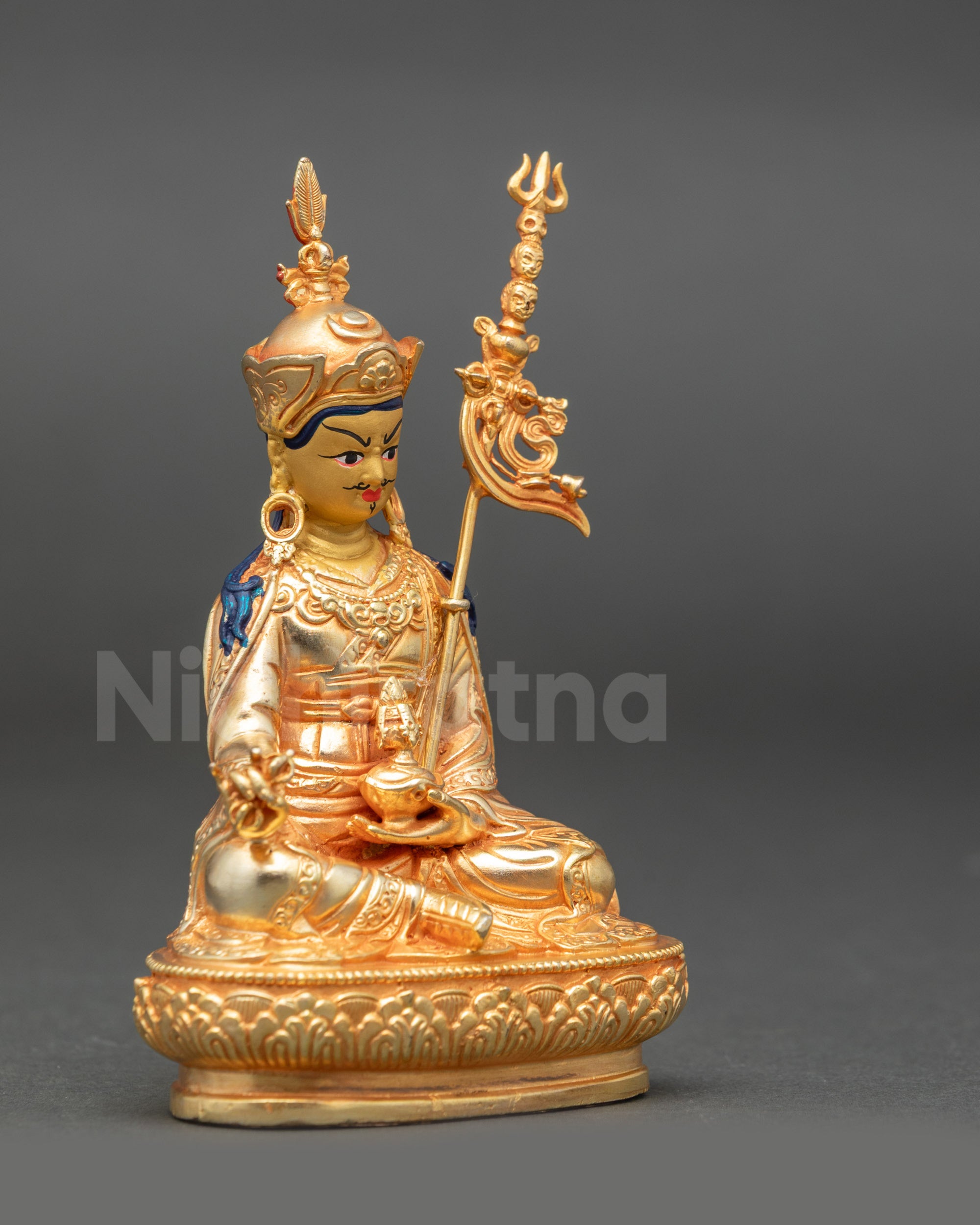 Side view of Guru Rinpoche statue showing vajra in right hand and kapala in left
