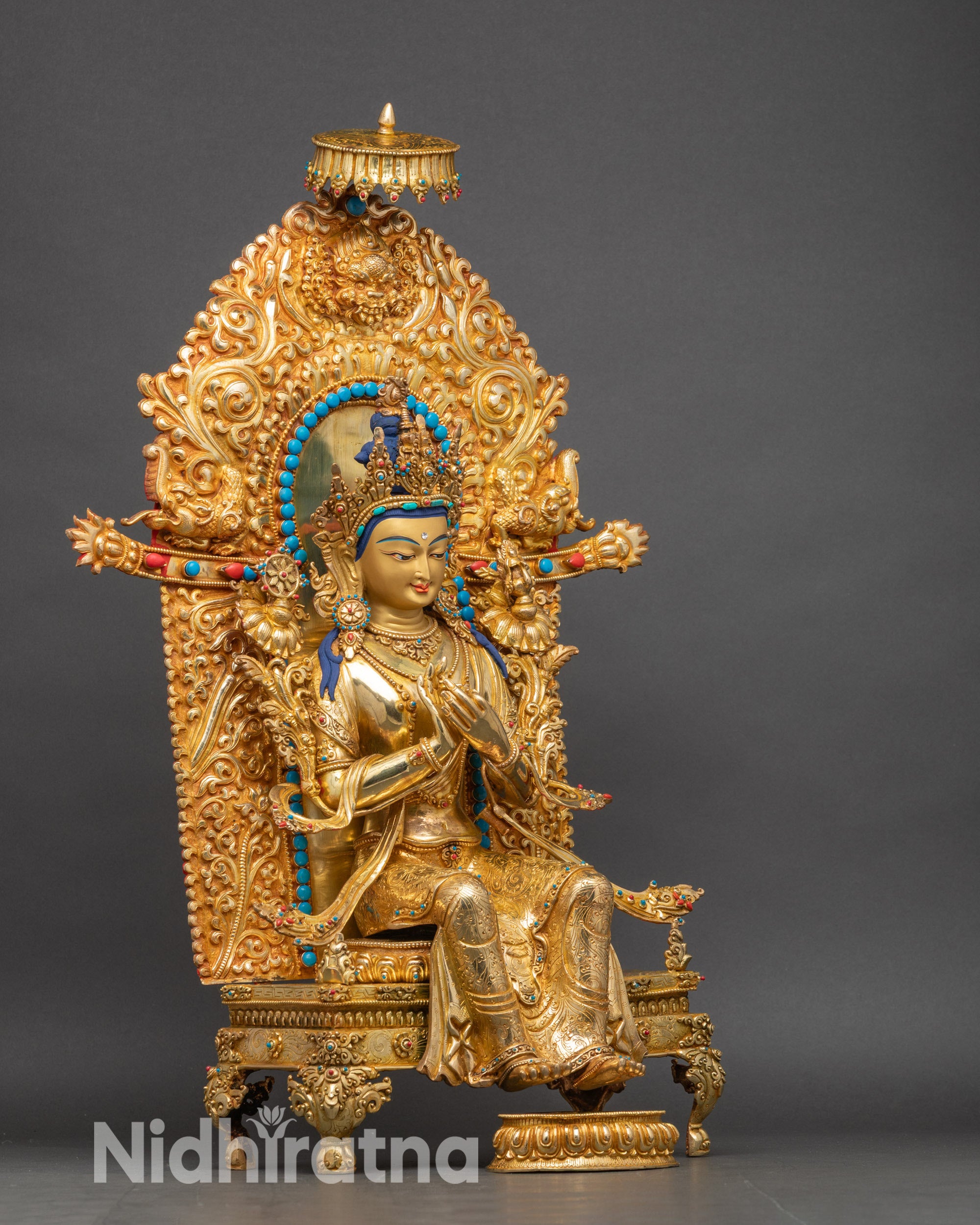 Side view of Maitreya Buddha sculpture highlighting intricate garments and lotus seat