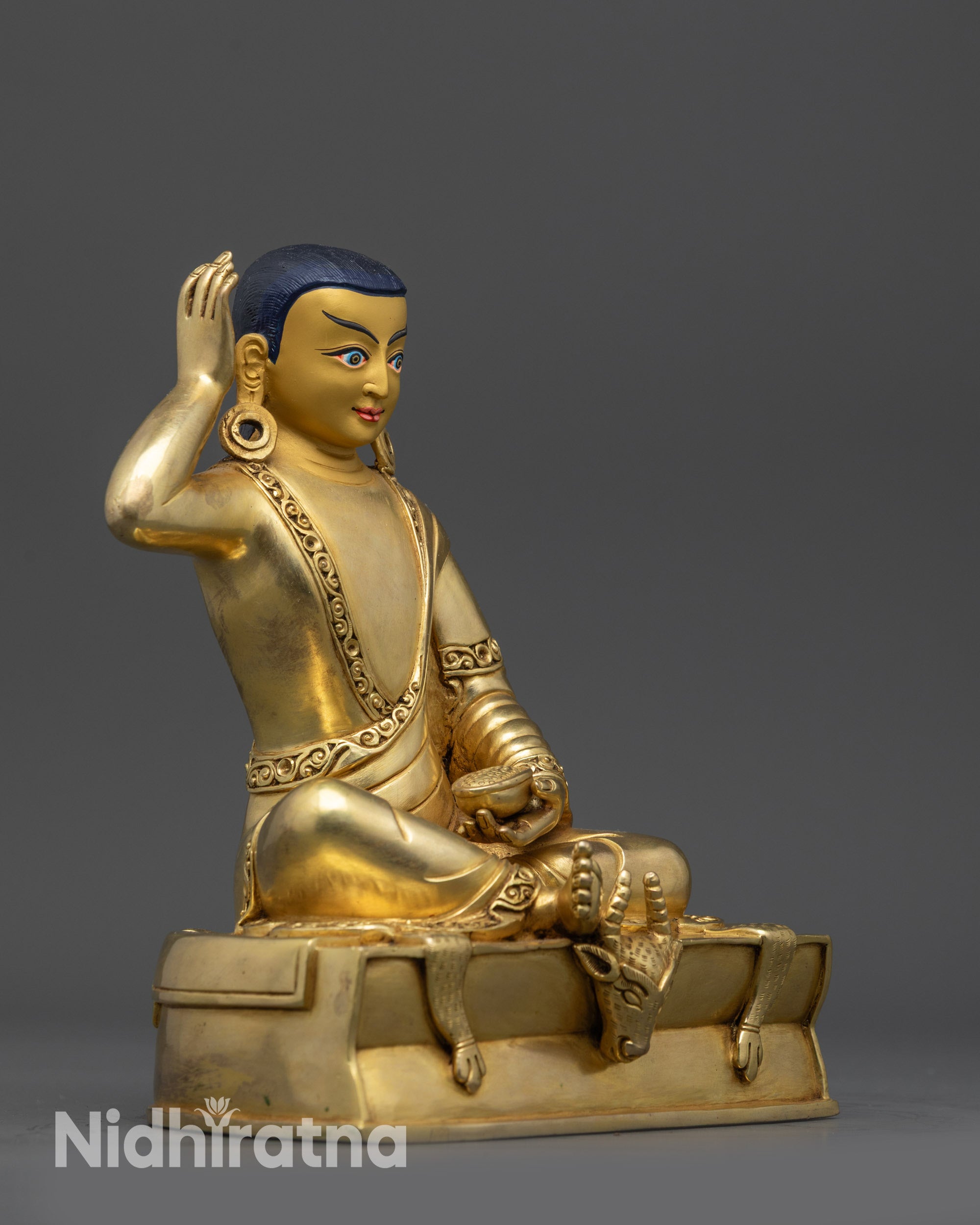 Side view of Milarepa statue gold gilded Buddhist master on deer skin seat with begging bowl handmade in Nepal.