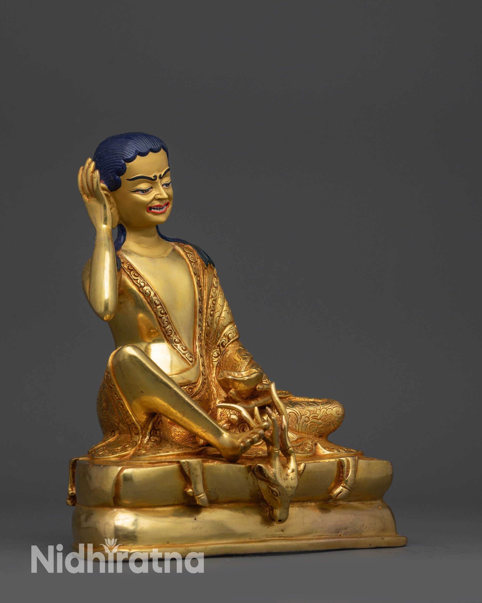 Side view of Milarepa statue highlighting intricate robe patterns and holding kapala