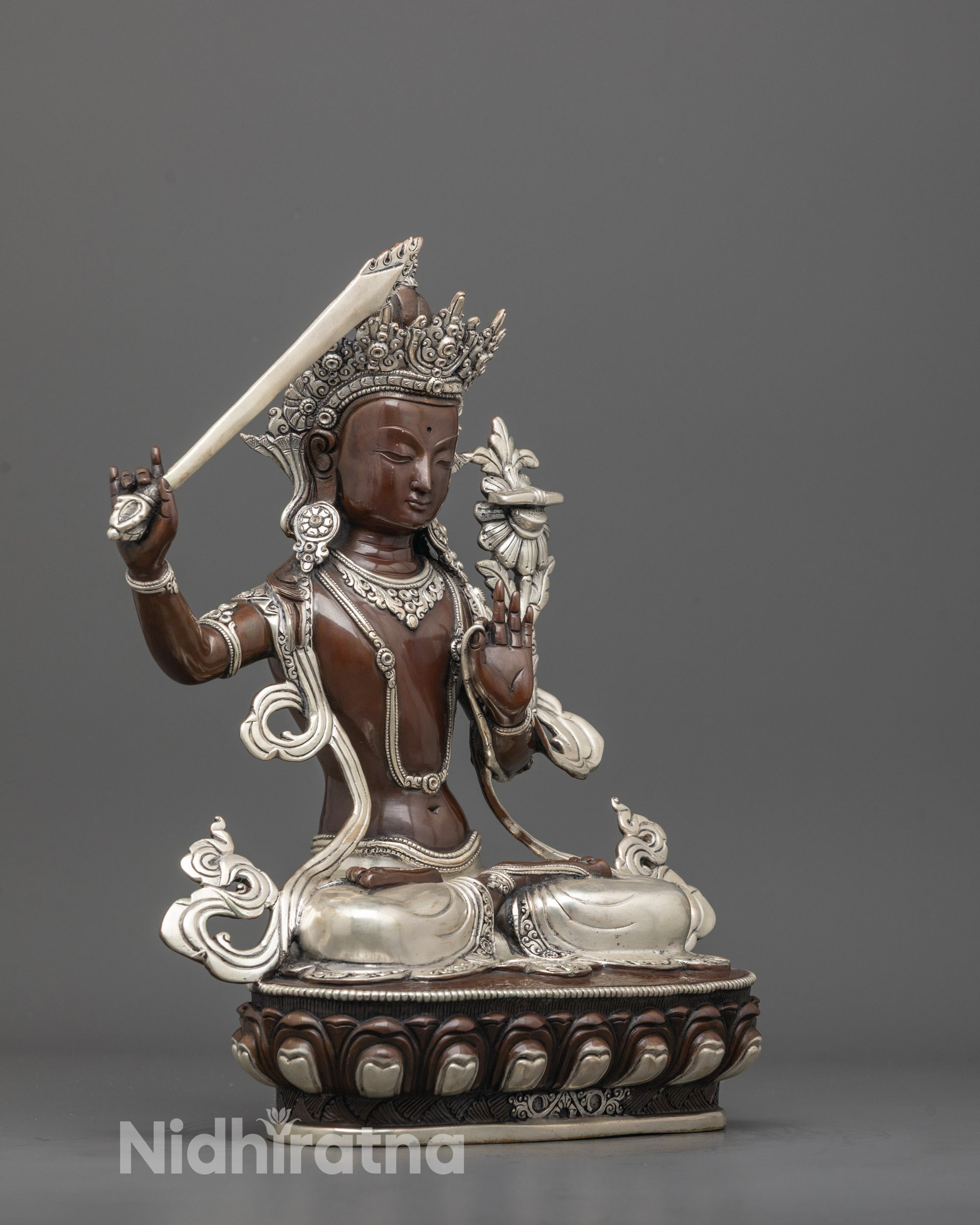 Side view of oxidized copper Manjushri statue showing silver robe and utpala flower