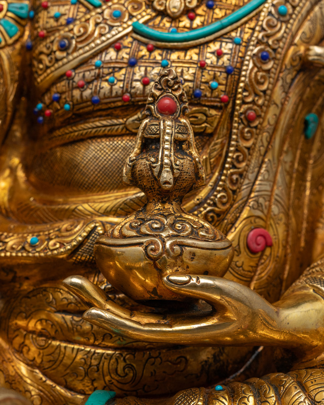 Symbolic Buddhist ritual objects |vajra scepter and skull cup | in hands of Guru Rinpoche statue, representing wisdom and transformation in Tibetan Buddhism
