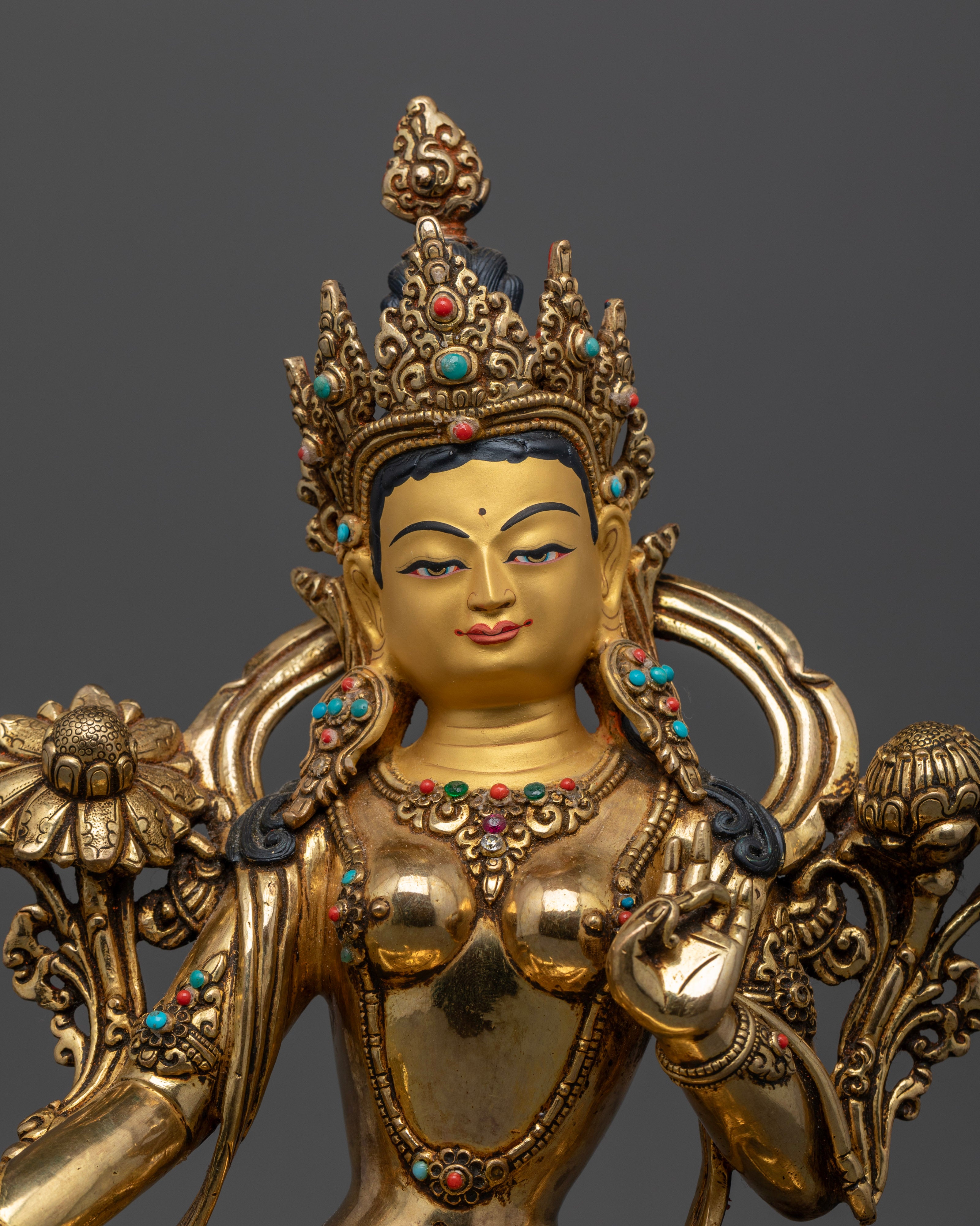 The Green Tara statue’s serene, gold-plated face, highlighting intricate detailing and the refined expression of compassion and grace.