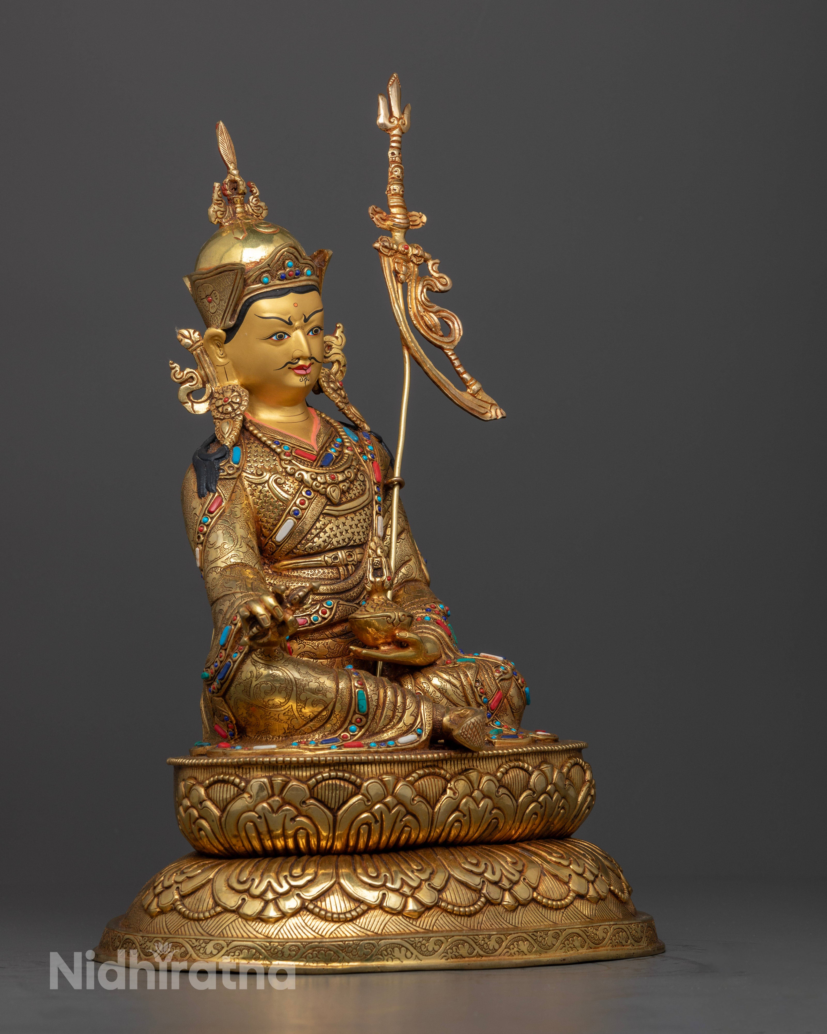 The Guru Rinpoche statue, emphasizing the detailed craftsmanship of his flowing robes, lotus seat, and the brilliance of embedded semi-precious gems.