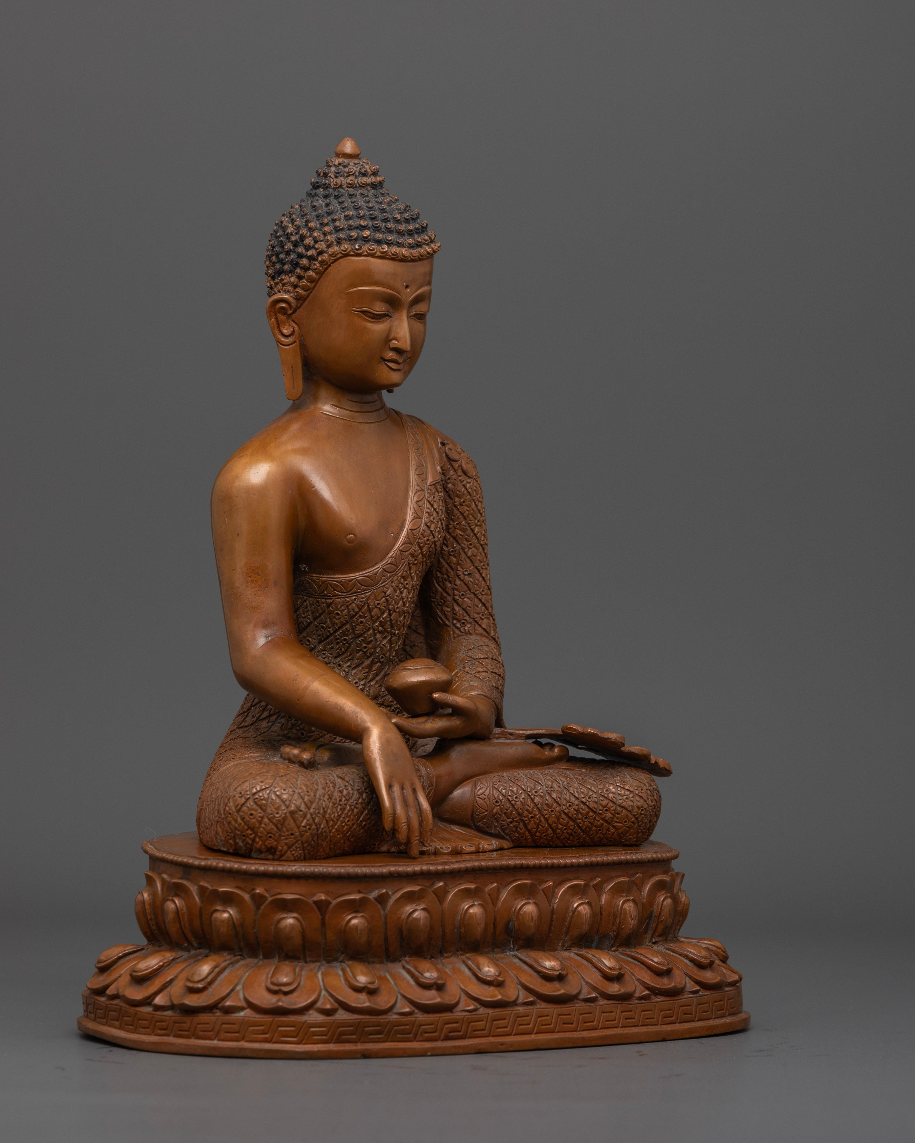 The oxidized Shakyamuni Buddha statue, highlighting its simplistic yet profound design and the intricate artistry on the robes.