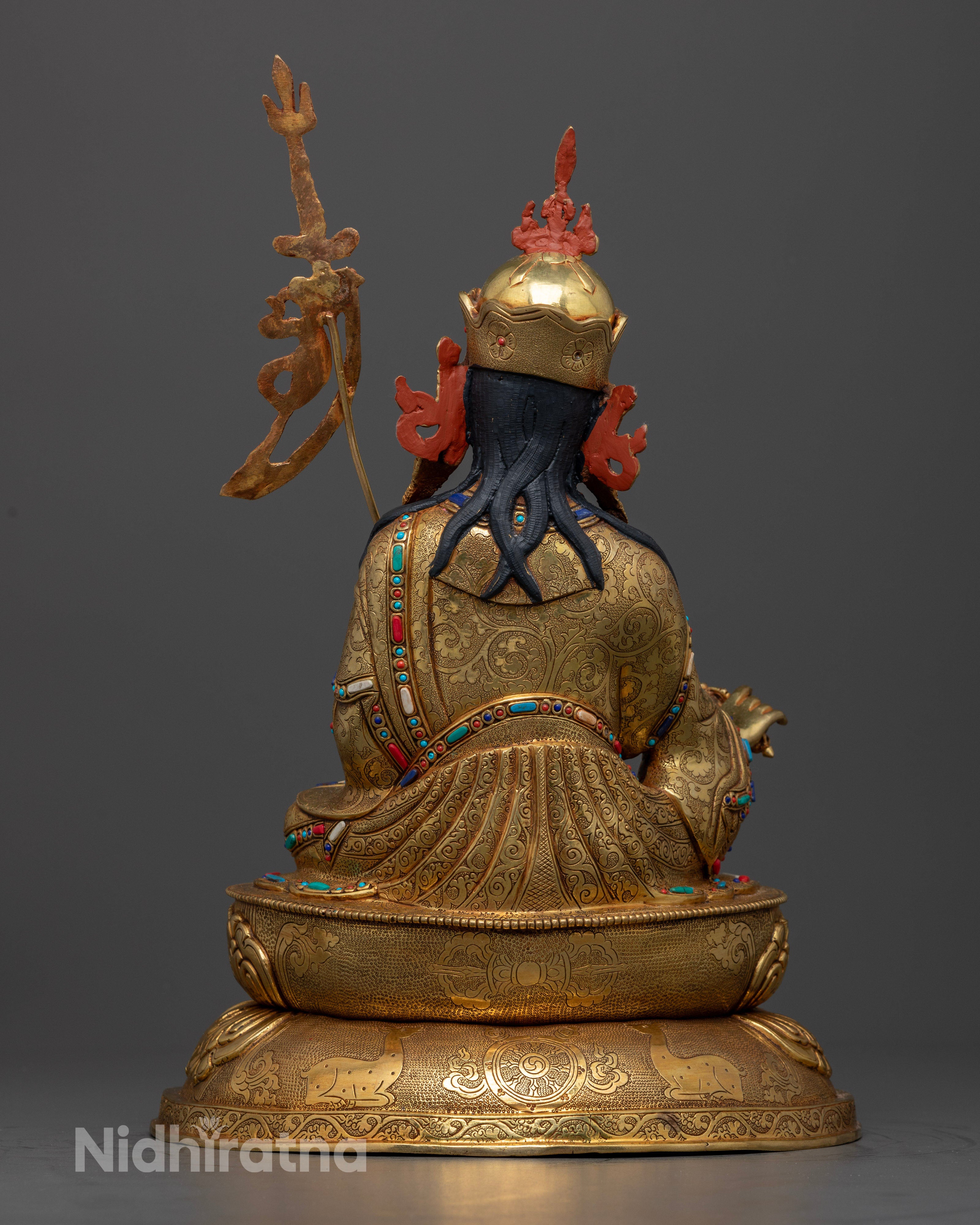 The Guru Rinpoche statue seated serenely on a lotus throne, symbolizing purity and spiritual awakening, adorned with intricate details and semi-precious stones.