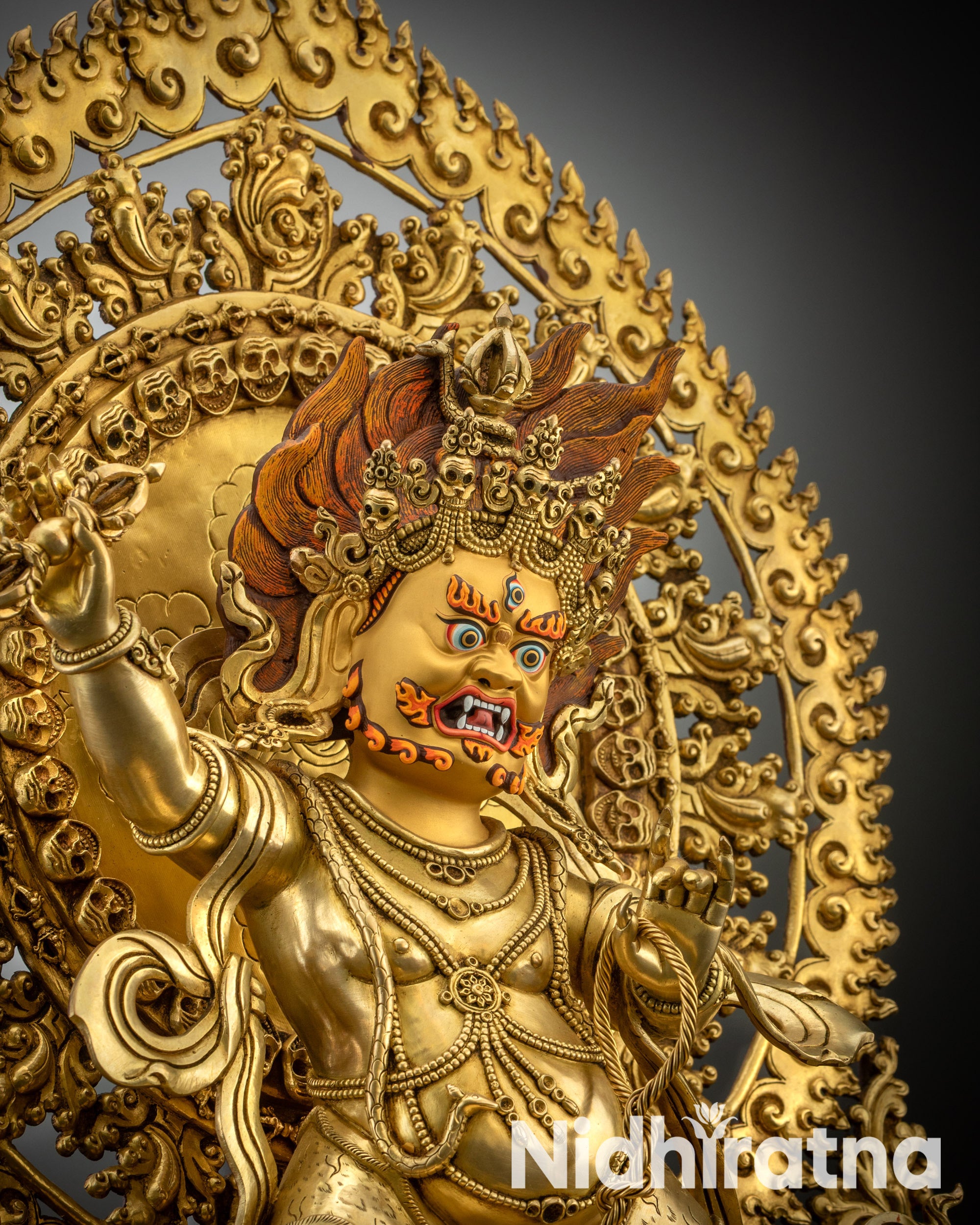 Upper close-up of Vajrapani statue showing gold-gilded face, flaming hair, and third eye