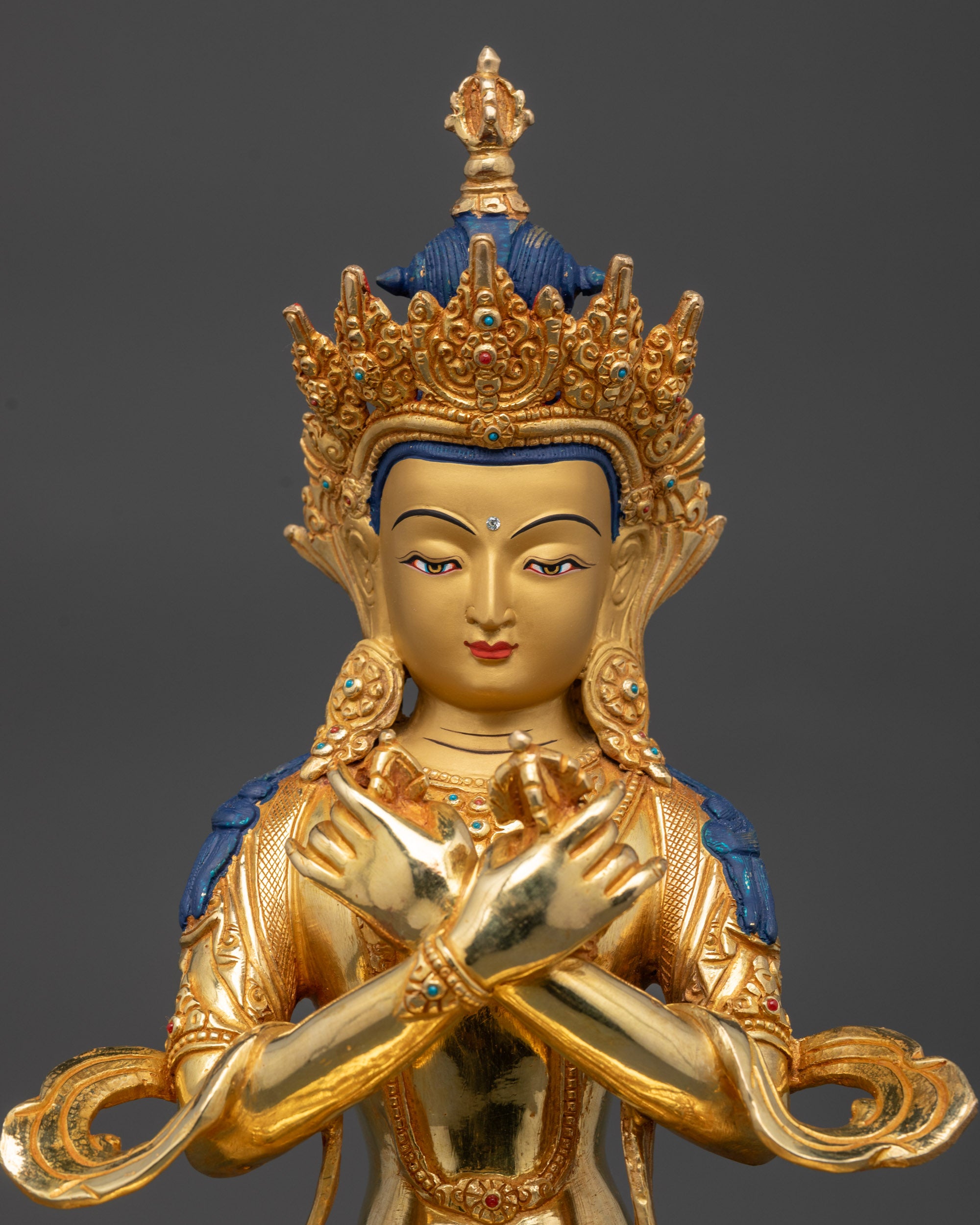 Vajradhara Buddha statue close up showing vajra and bell in arms-crossed pose