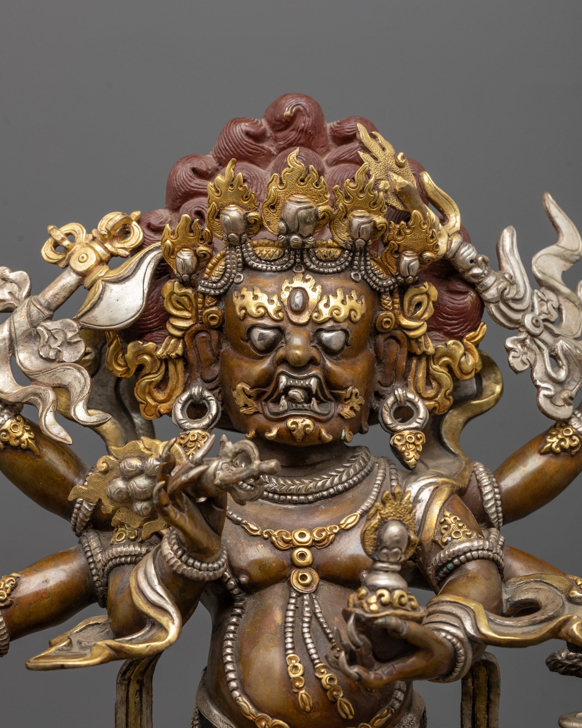 Close up of fierce Mahakala face showing detailed carvings and oxidized copper finish