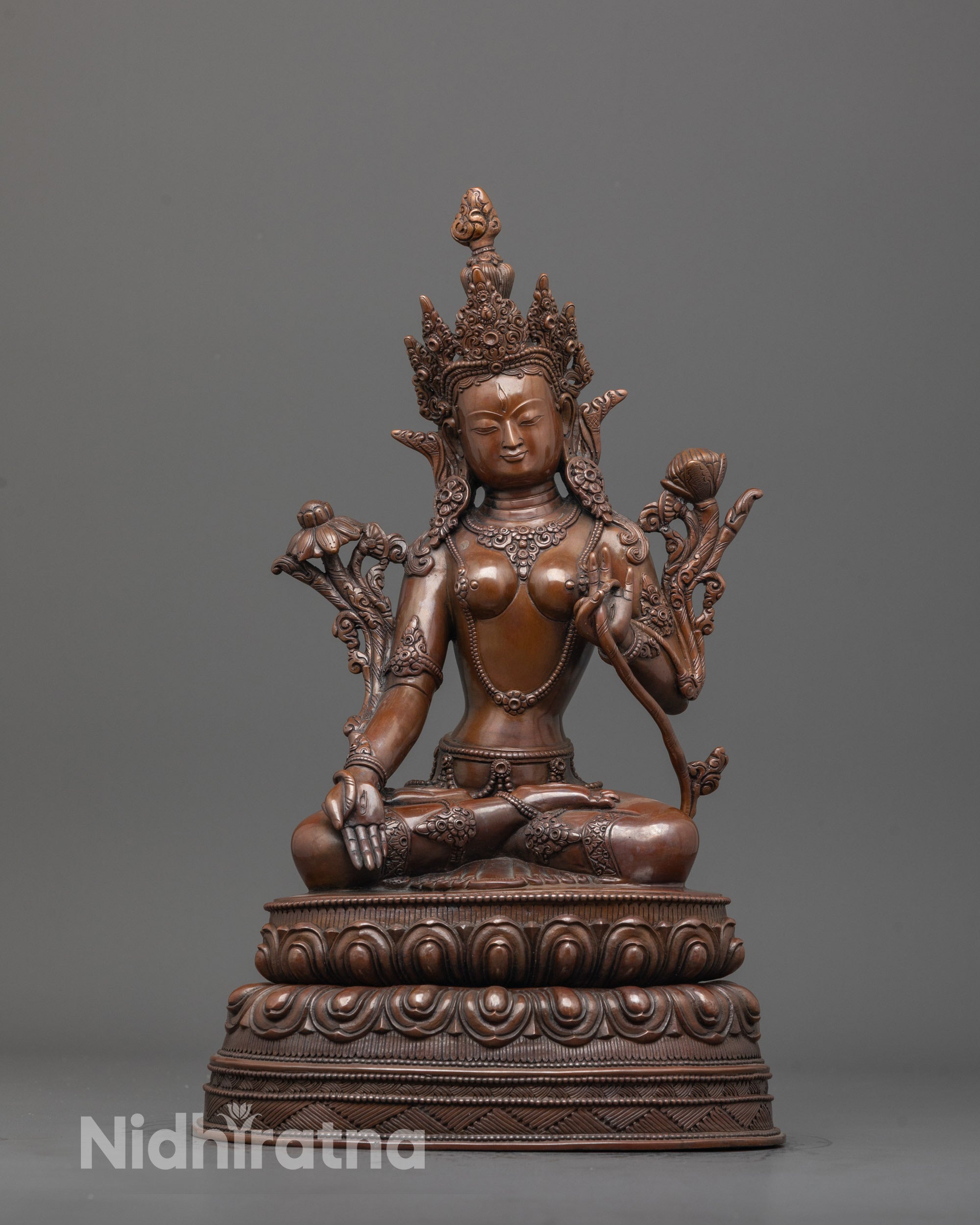 front view of oxidized white tara statue seated on double lotus base with sacred symbols
